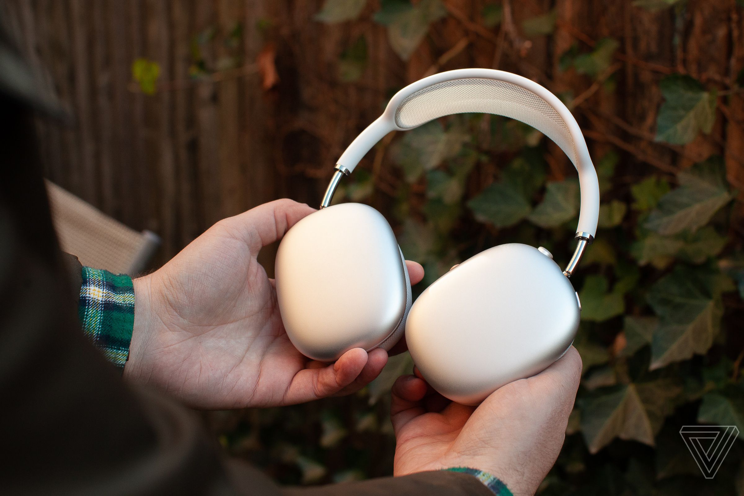 Hands holding the silver Apple AirPods Max.