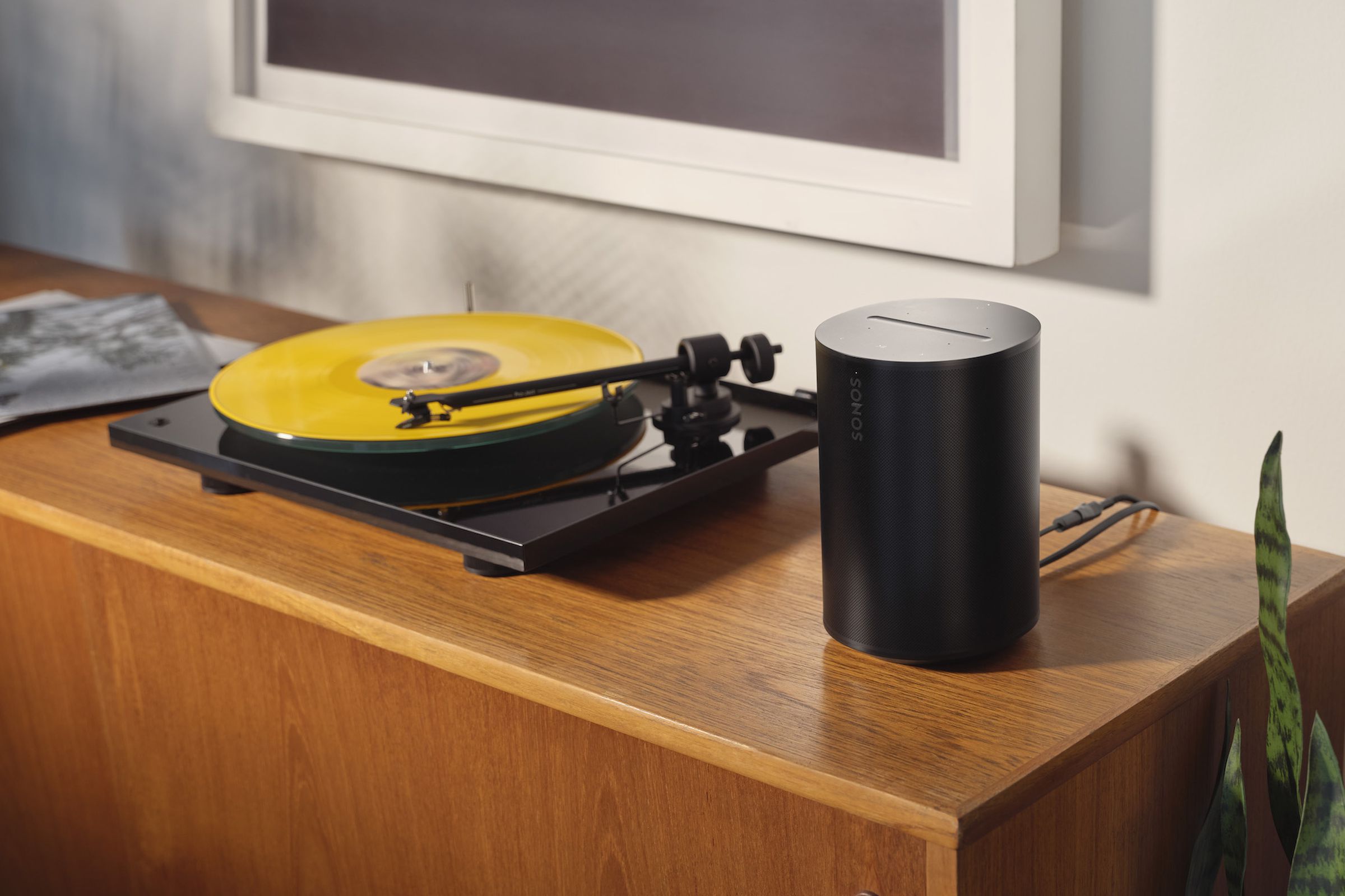 A photo of a Sonos Era 100 beside a turntable.