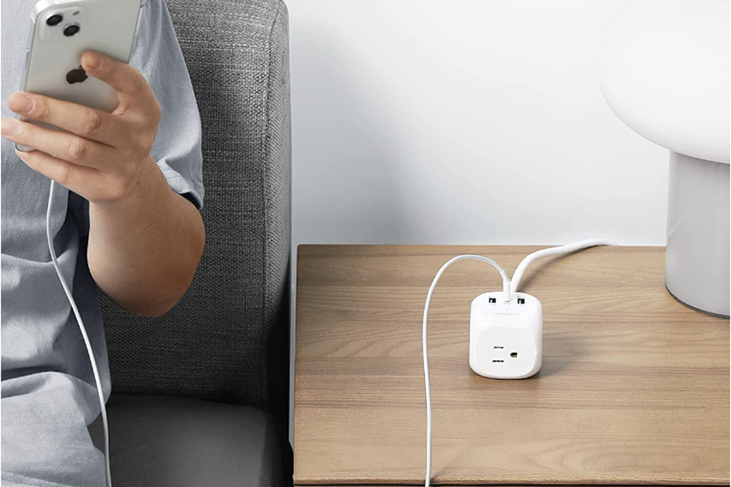 Anker cube power strip on table in between a person with a phone and a computer