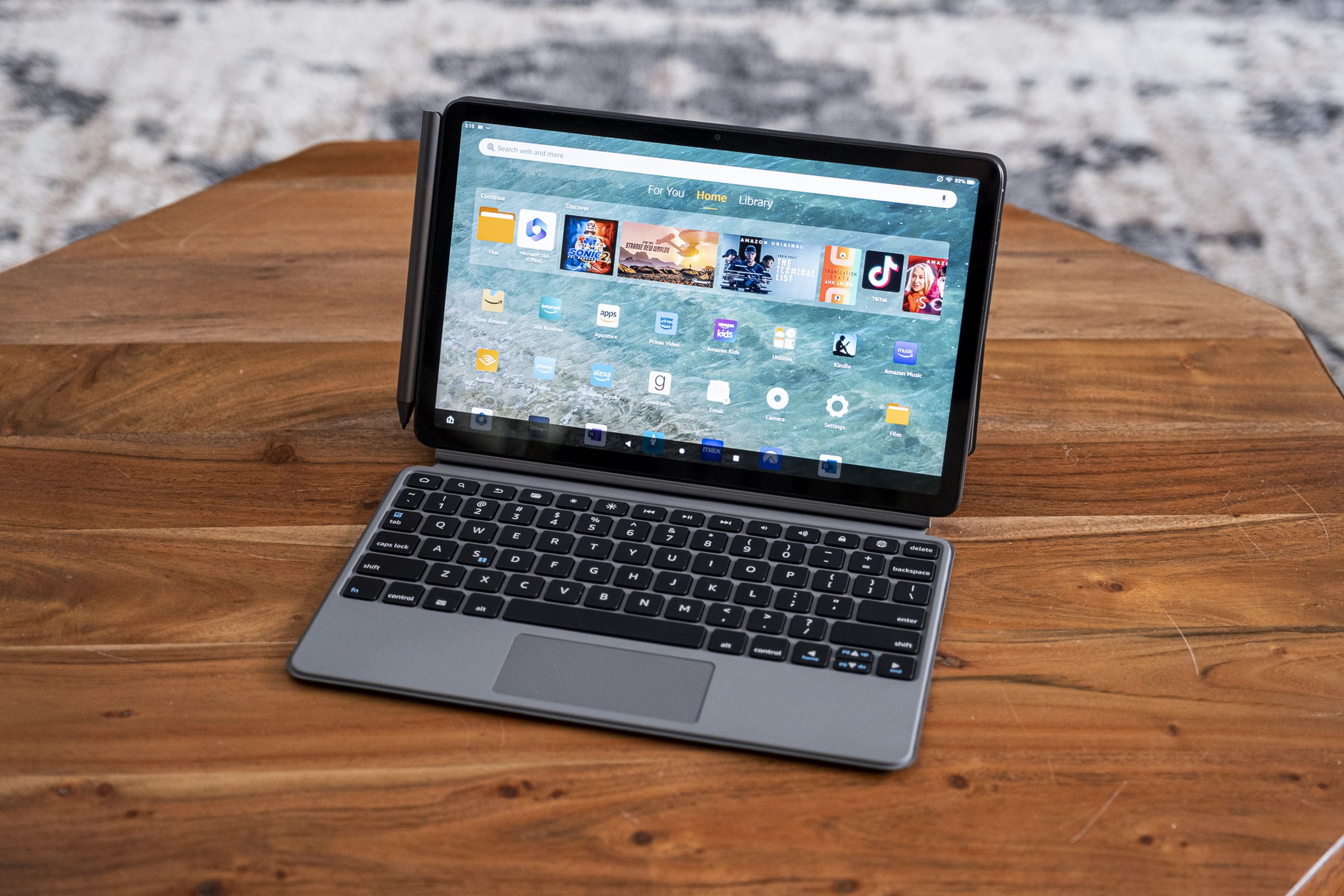 An Amazon Fire Max 11 tablet in its keyboard case on a wooden table.