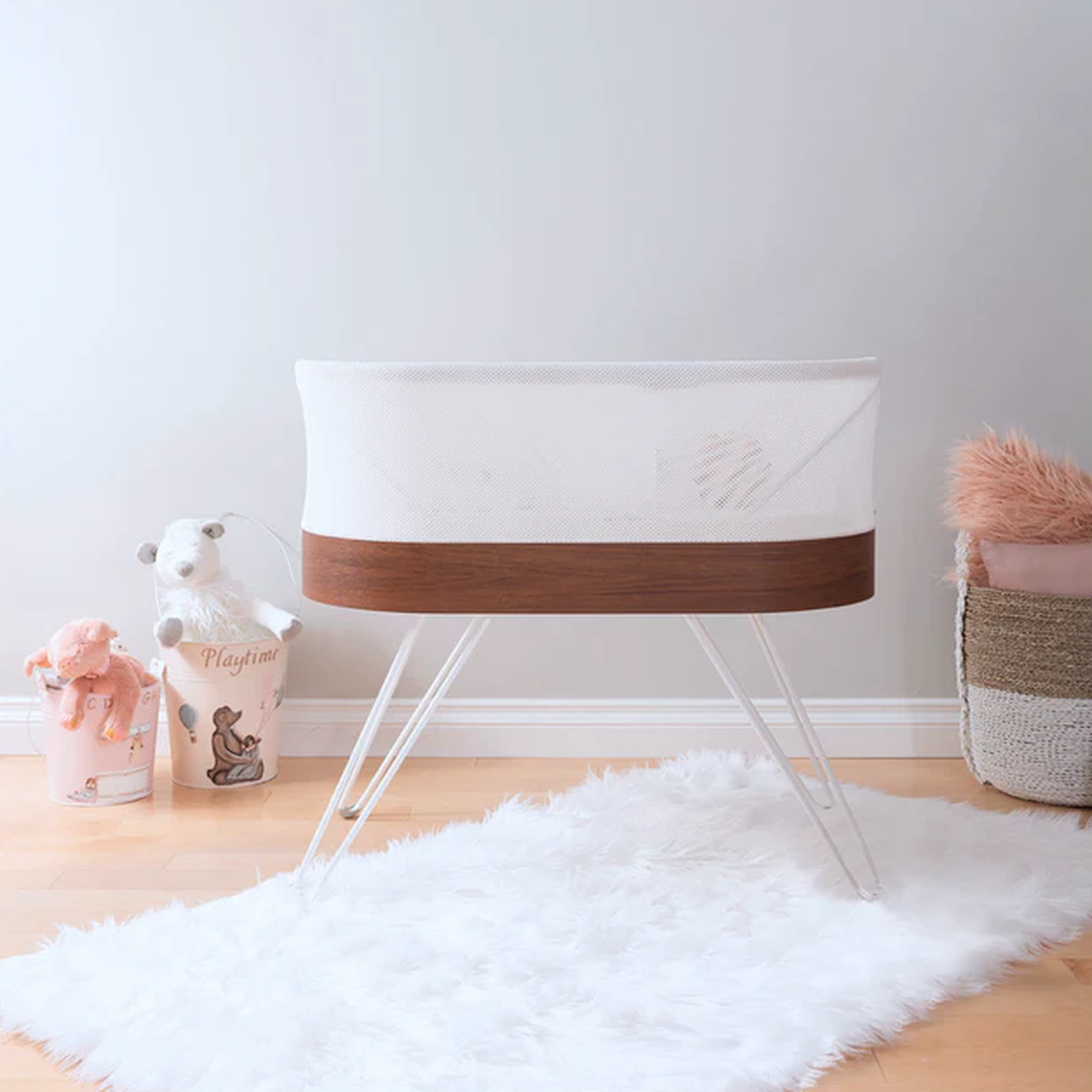 Picture of a Snoo bassinet on a white rug surrounded by baby toys.