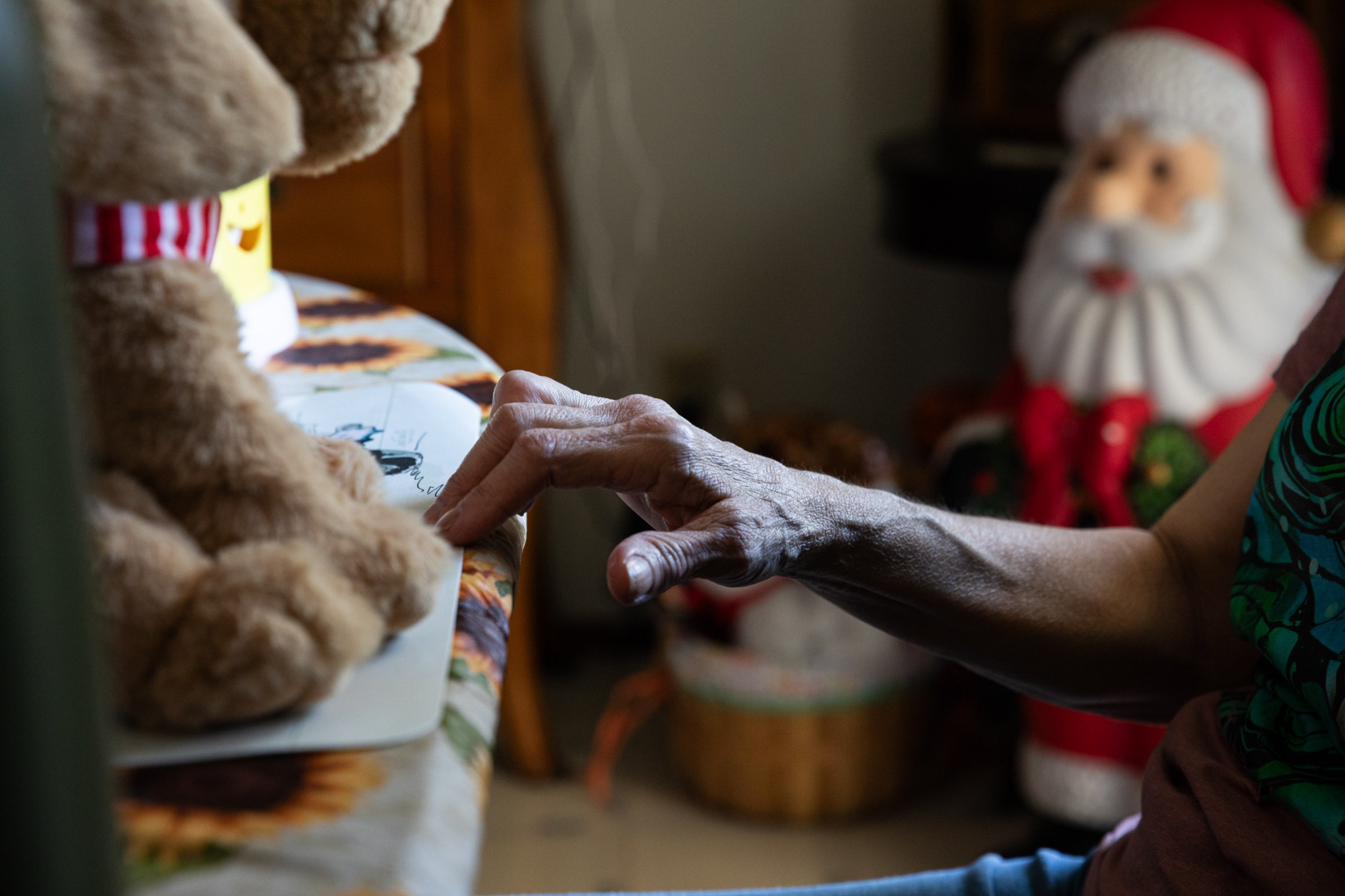 A hand touches a piece of paper sitting on a ledge with a stuffed toy on top of it.