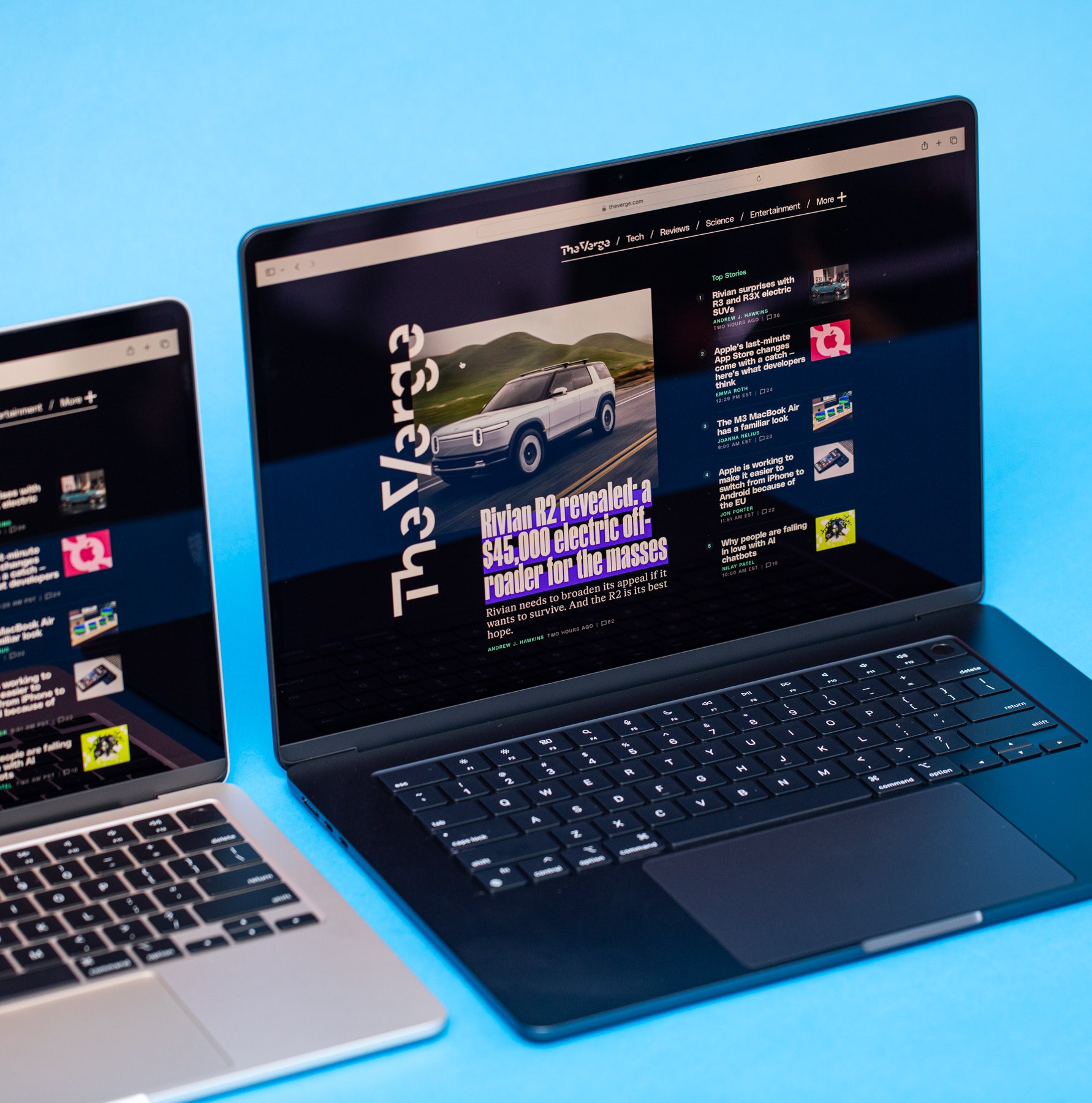 An angled photo of two open and powered on laptops against a light blue background.