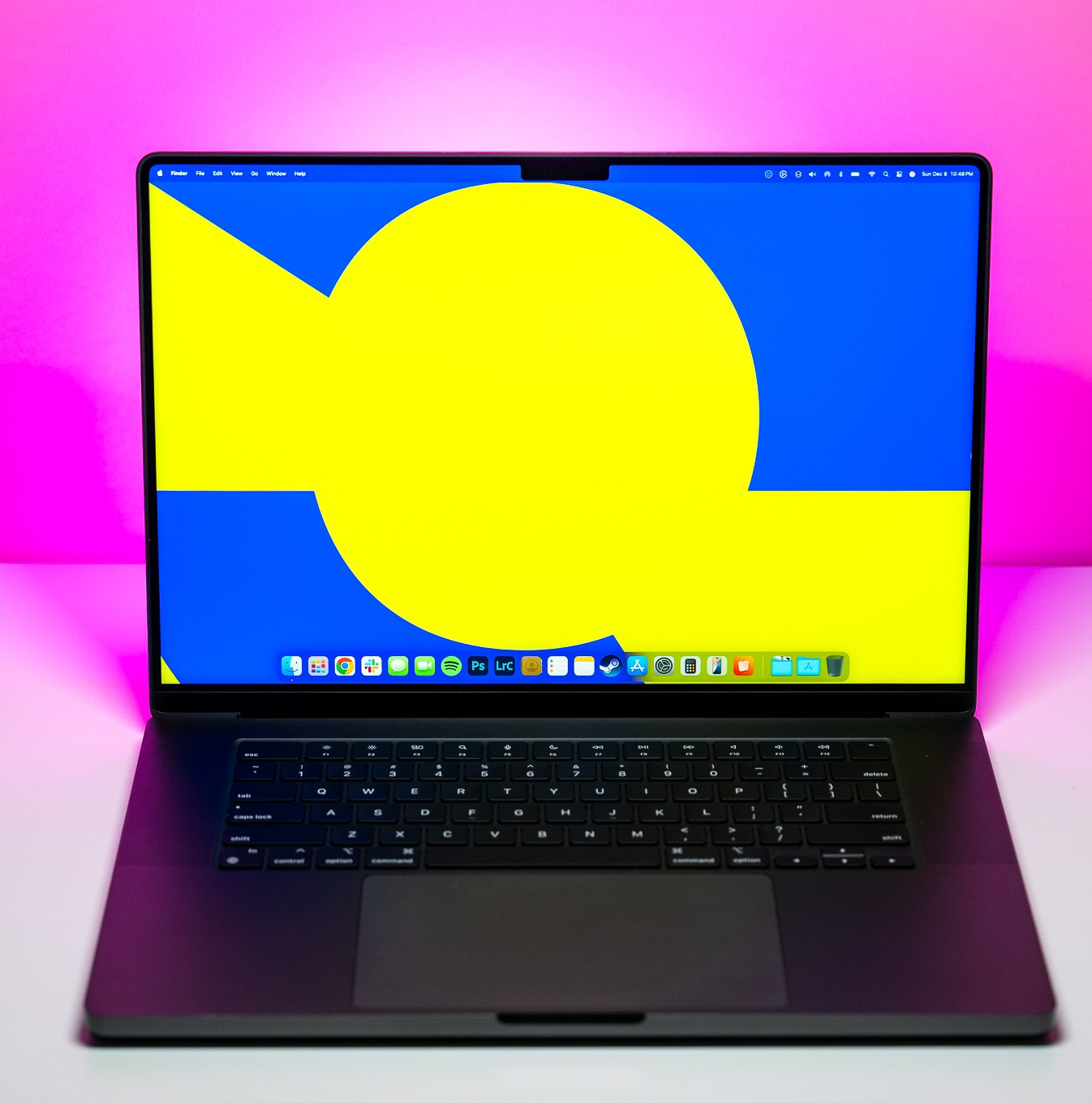 The 16-inch MacBook Pro with M4 Max chip on a white table with pink background.