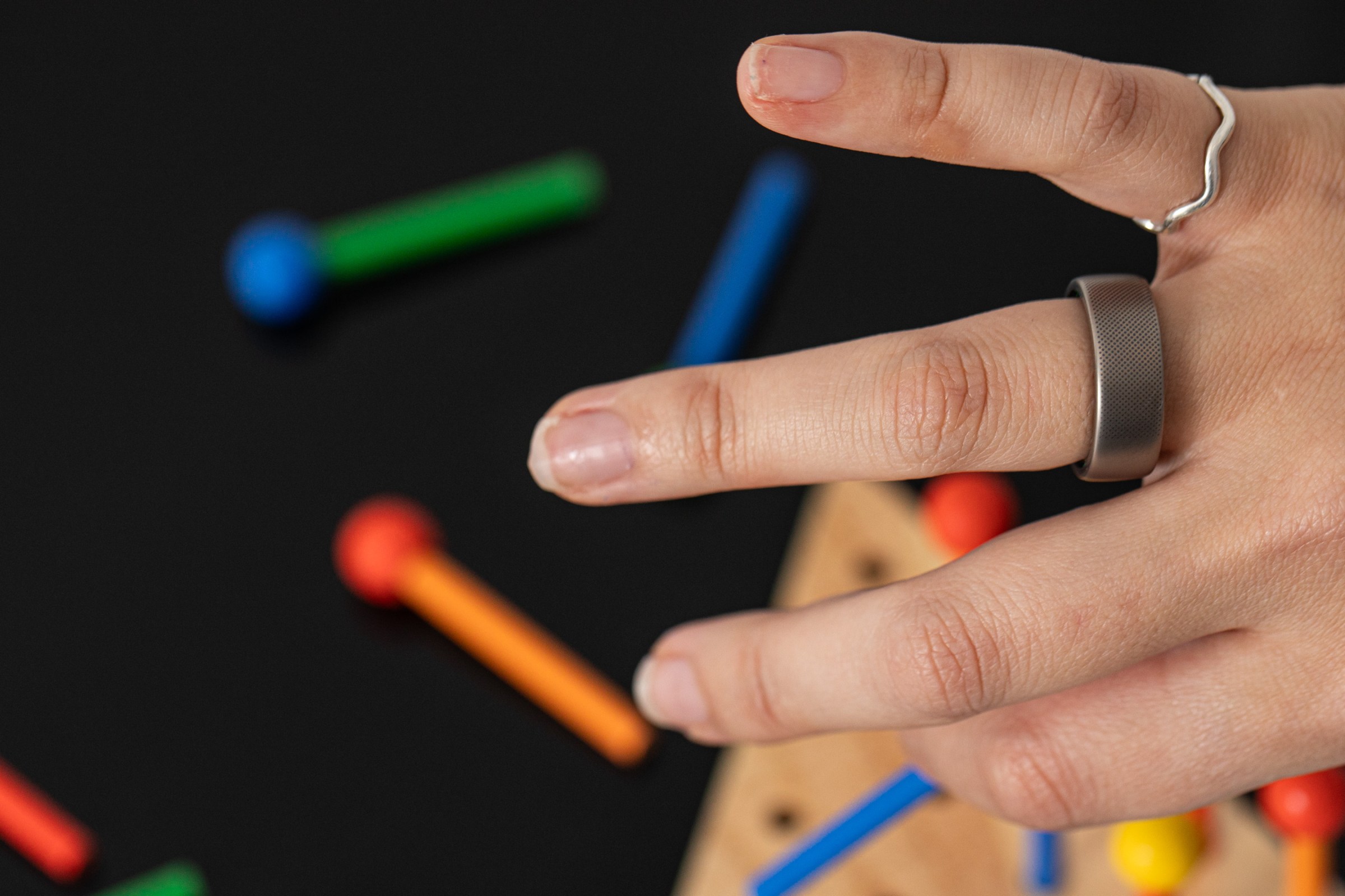 Person wearing Amazfit Helio ring with colorful wooden toy in background