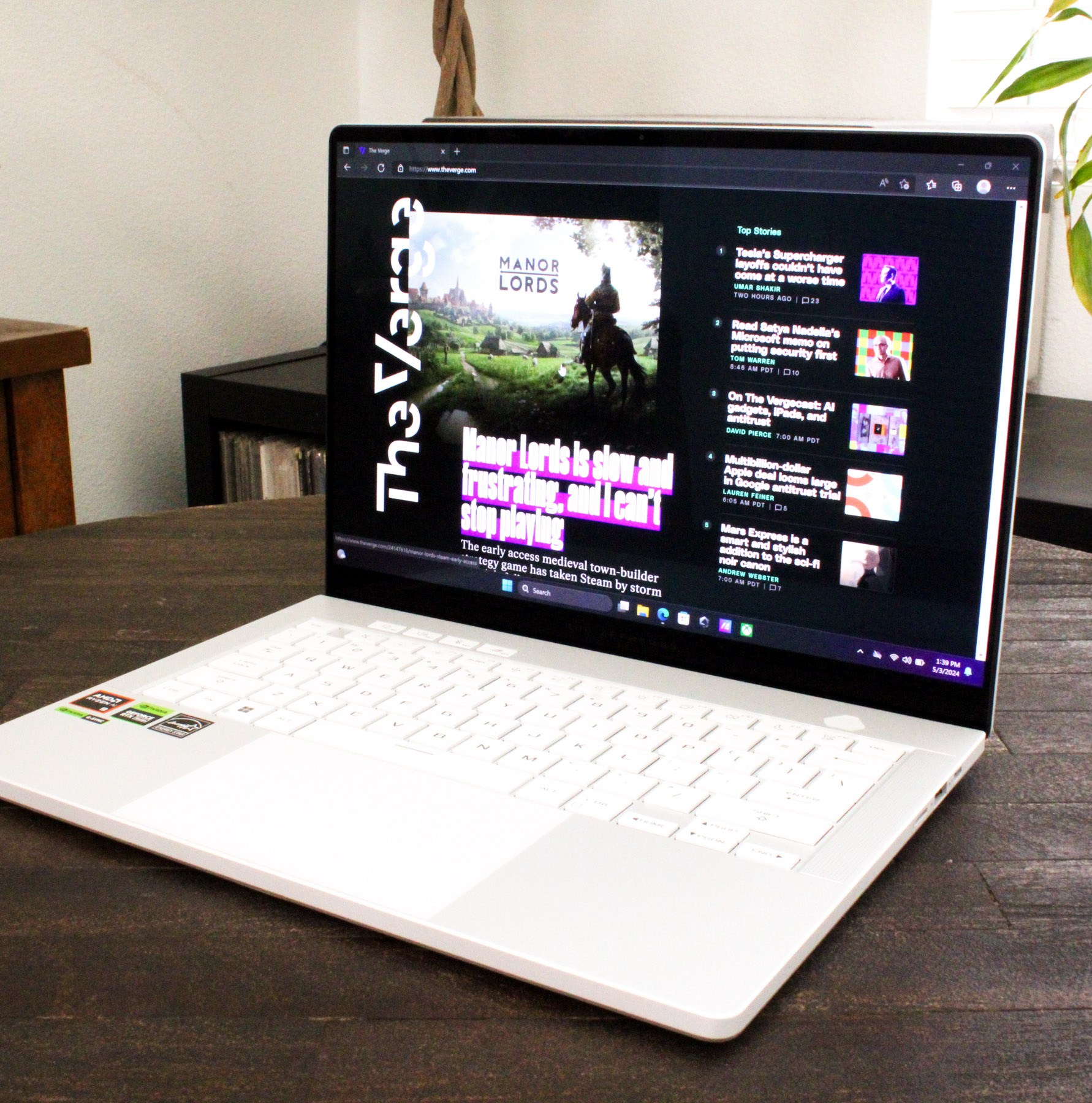 An open and powered on laptop sitting on top of a dark wood table.