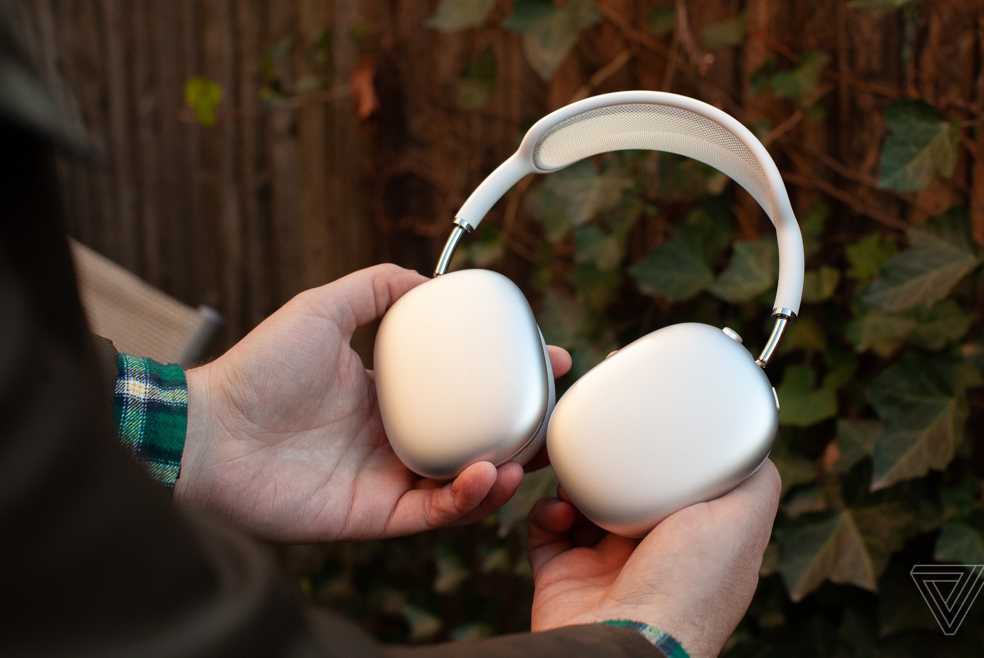 Hands holding the silver Apple AirPods Max.