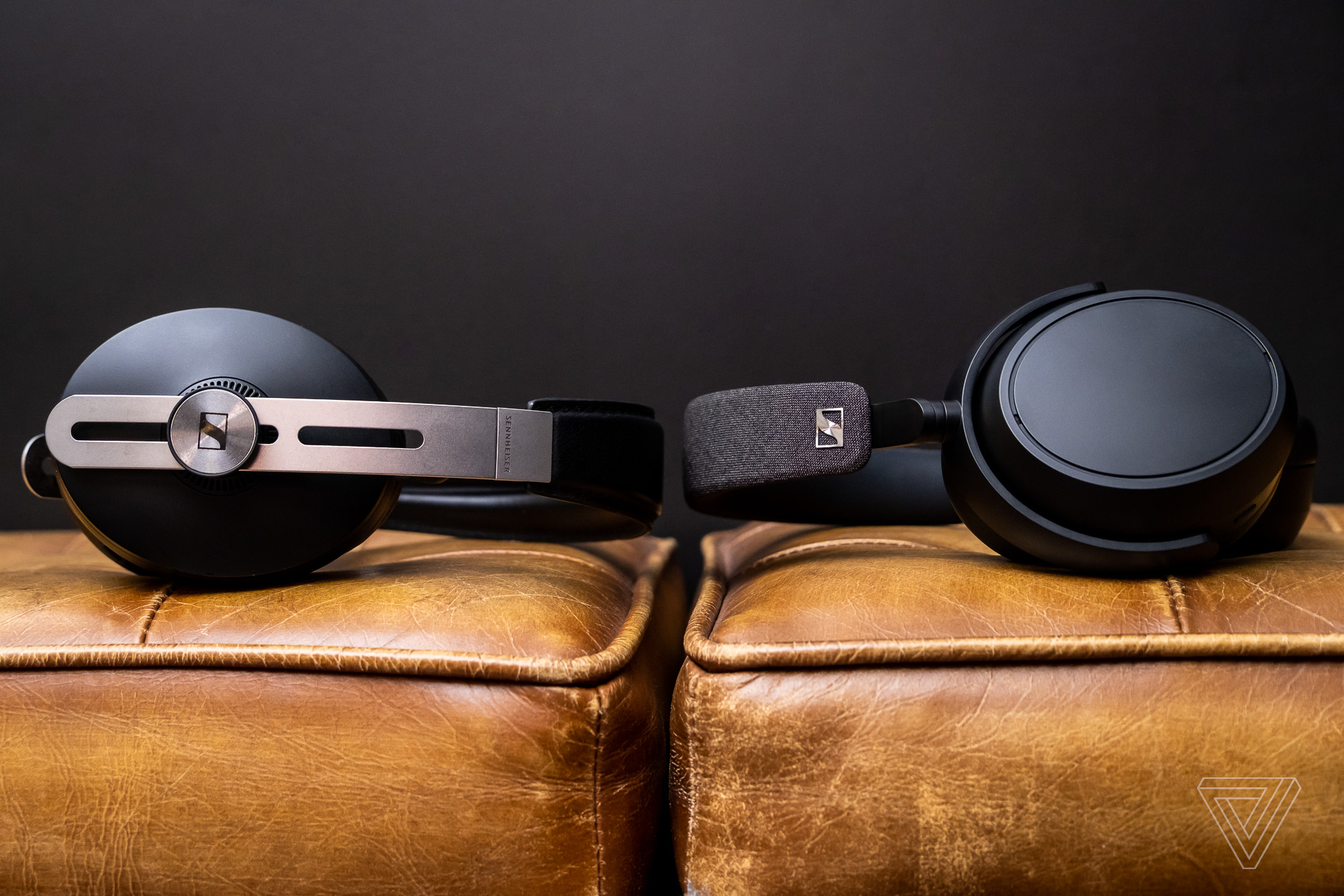 The Sennheiser Momentum 3 and Sennheiser Momentum 4 headphones facing each other while lying on a couch.