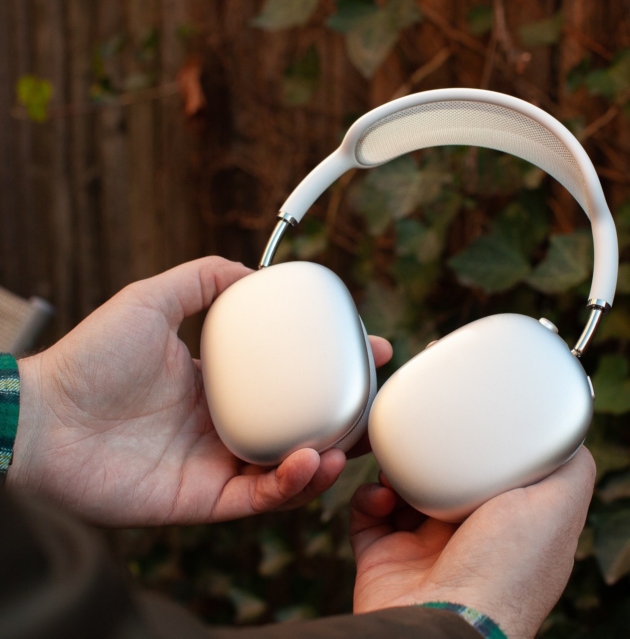 Hands holding the silver Apple AirPods Max.