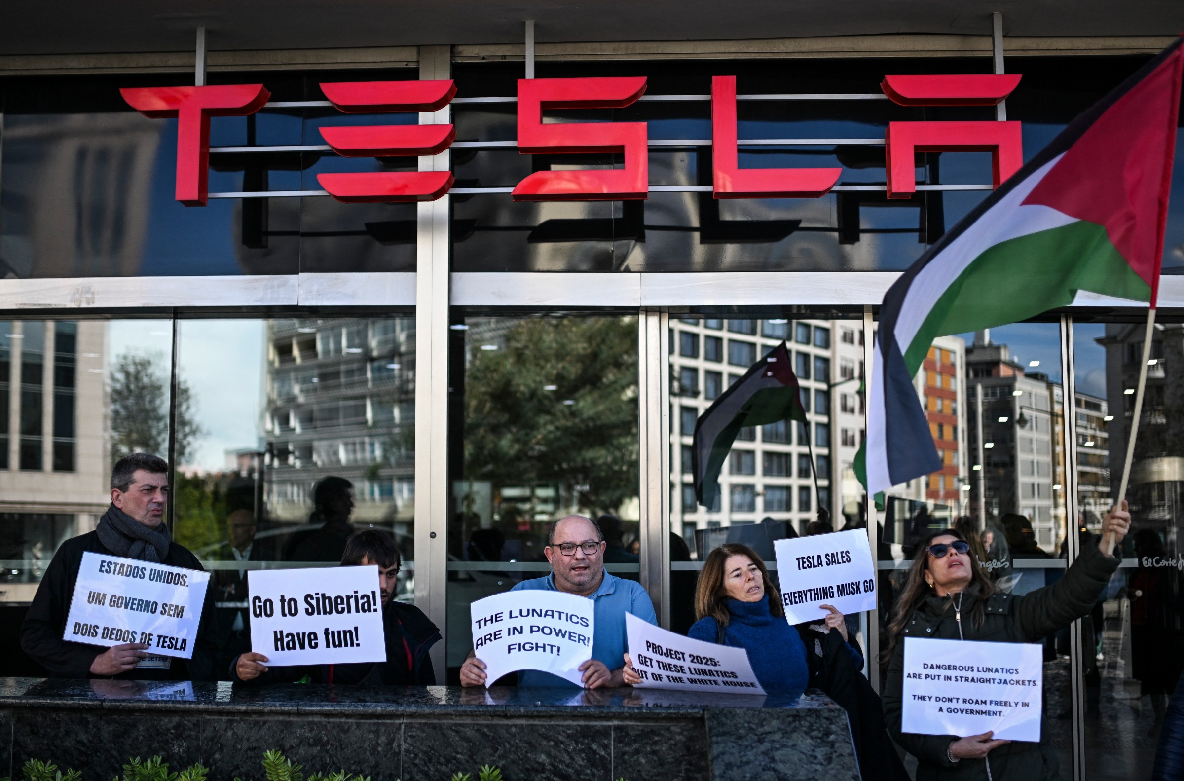 Demonstrators hold signs at Tesla’s dealership in Lisbon.