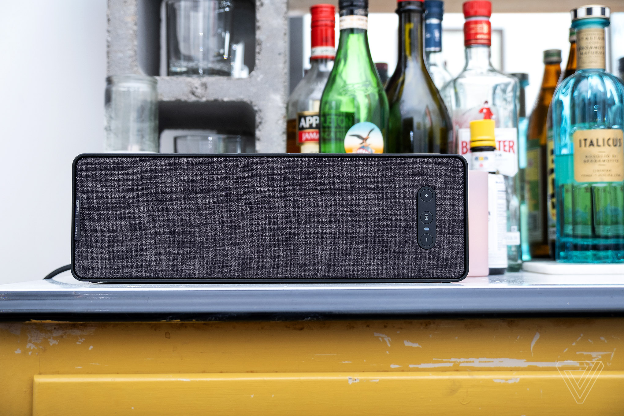 A photo of the Ikea Symfonisk Bookshelf Speaker with bottles behind it.