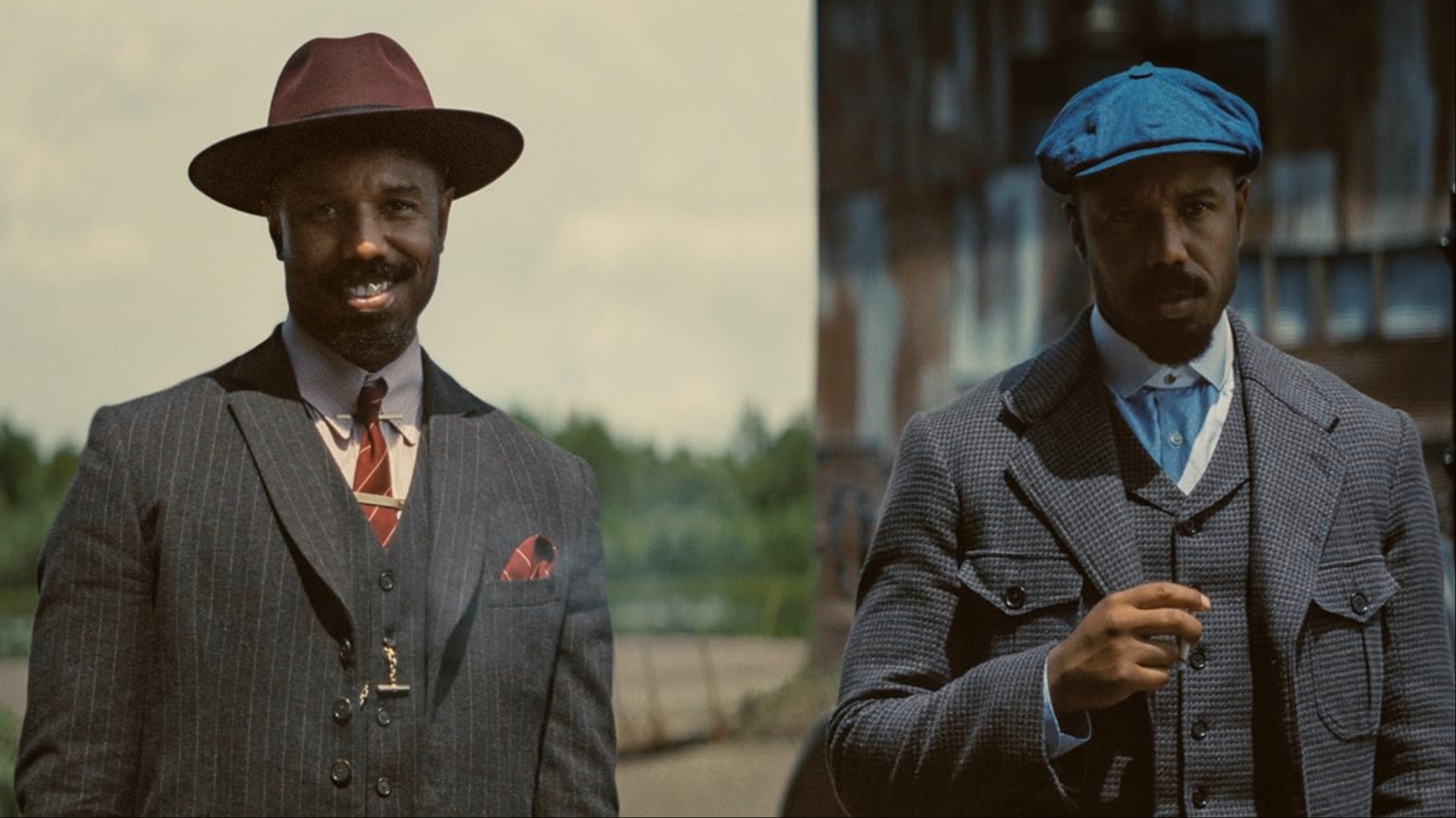 Two men smirk while standing next to each other.