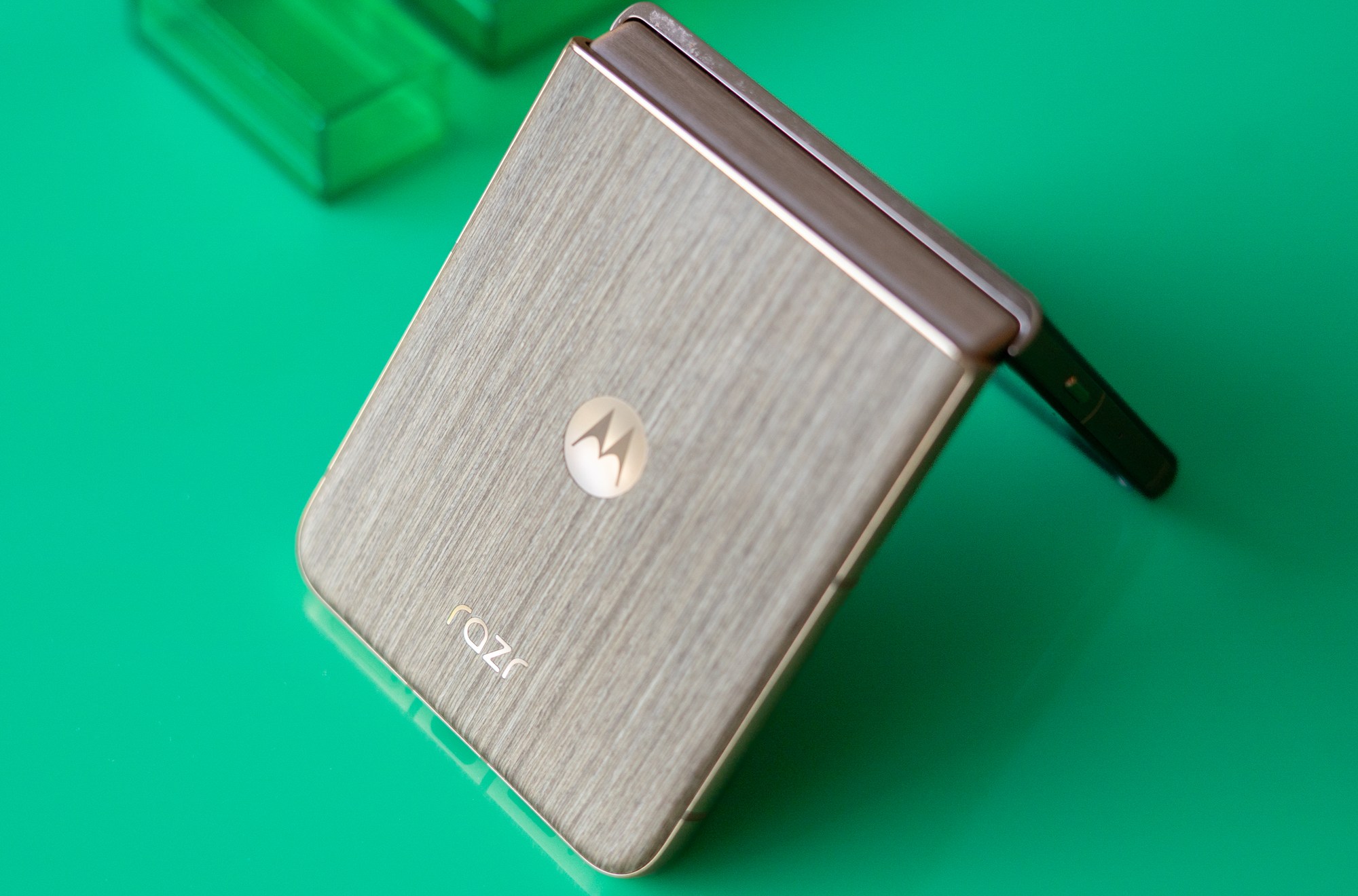 Motorola Razr with wood back panel partially unfolded on a green background