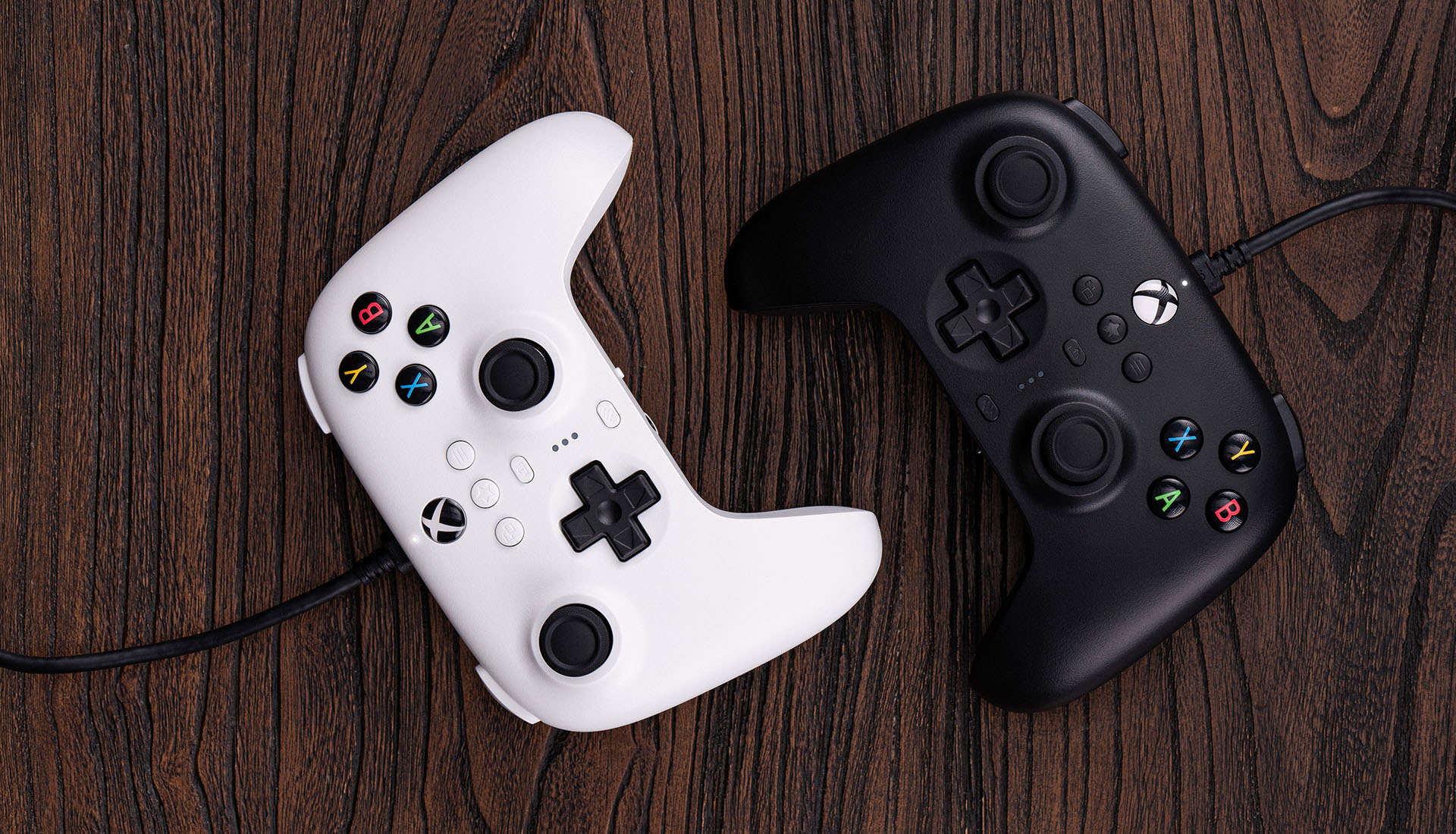 A pairof 8BitDo Ultimate Wired for Xbox controllers on wooden table