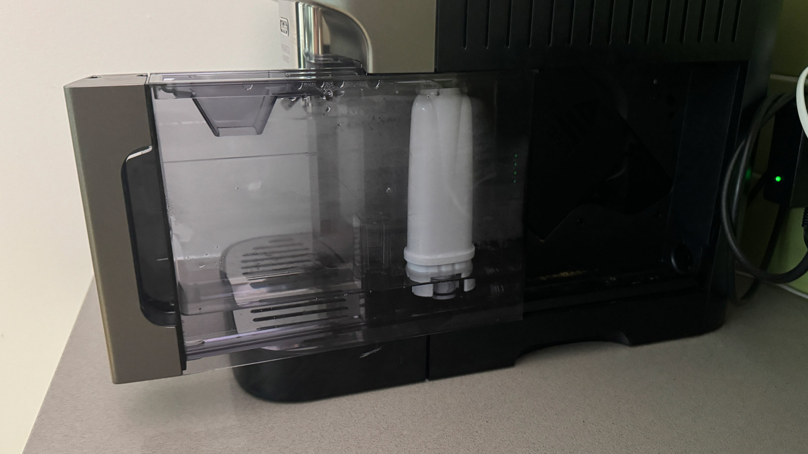 The water tank of the De'Longhi Magnifica Evo Next coffee machine removed half way.