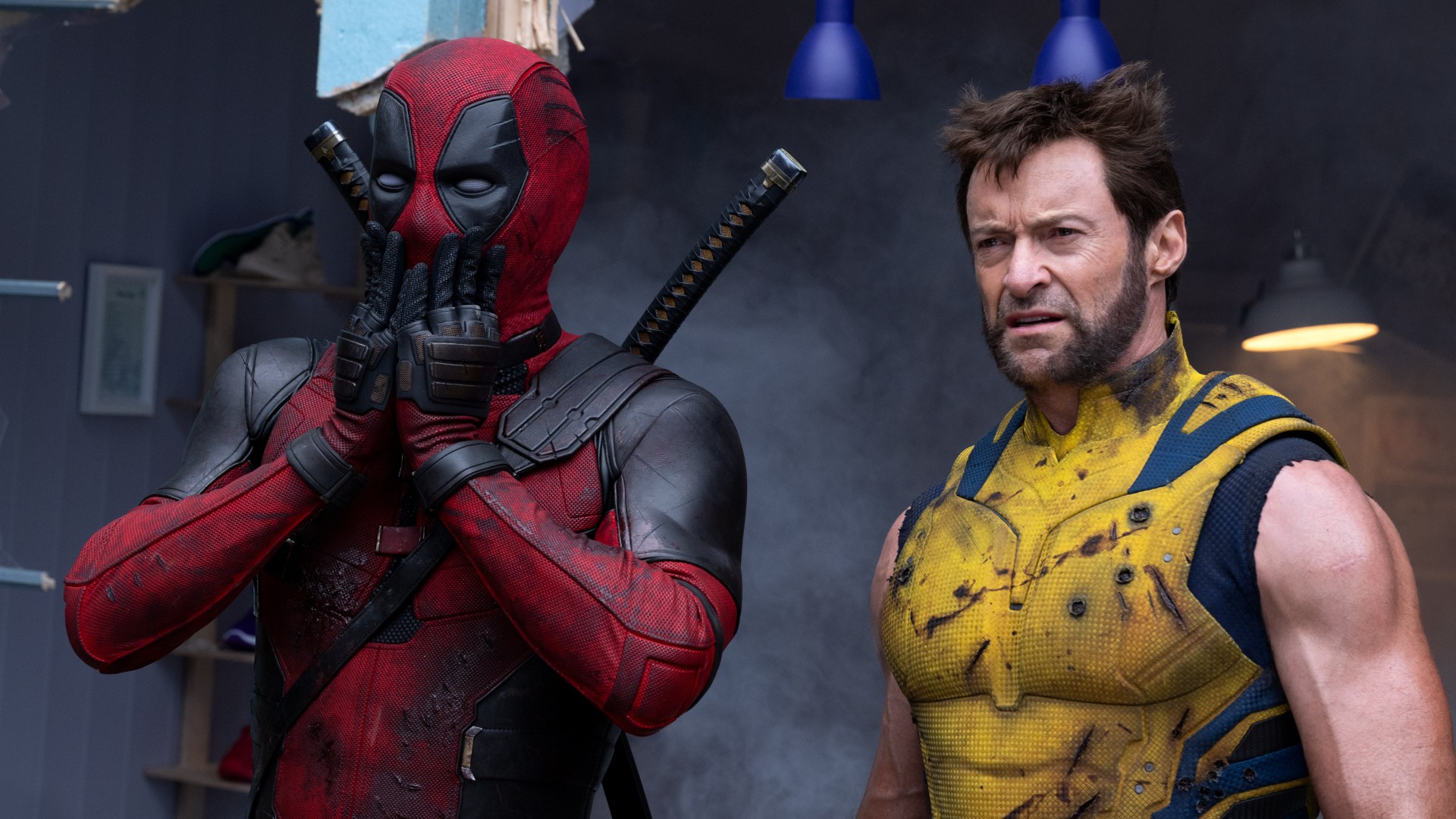 A masked Ryan Reynolds covers his mouth as Hugh Jackman glowers in a still from the movie