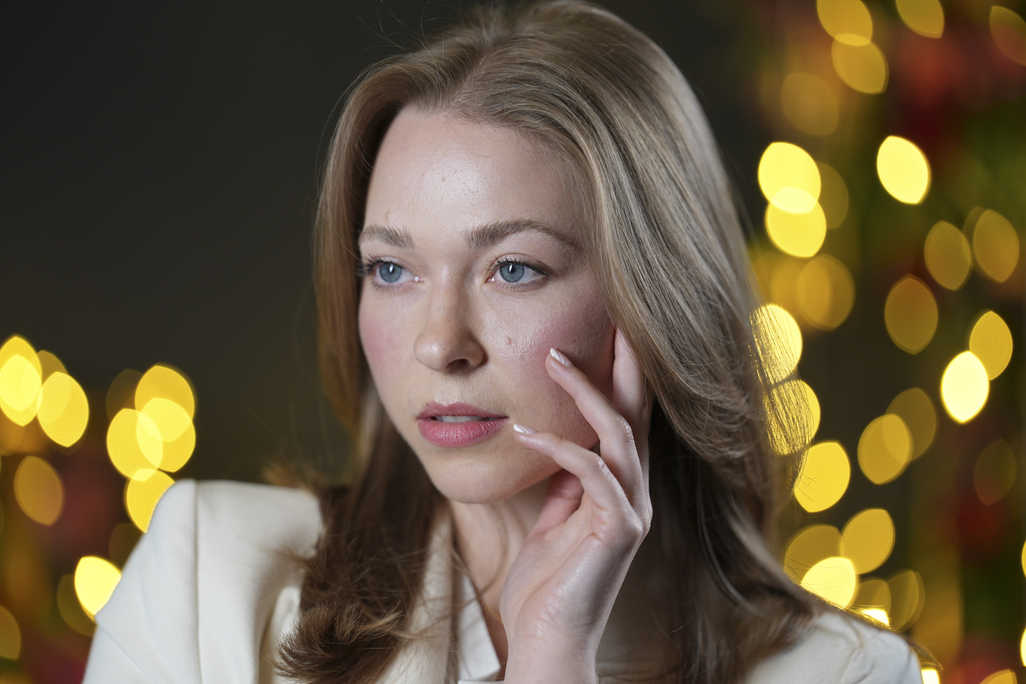 Portraits of a woman in smart jacket, in a studio with blurred fairy lights in background