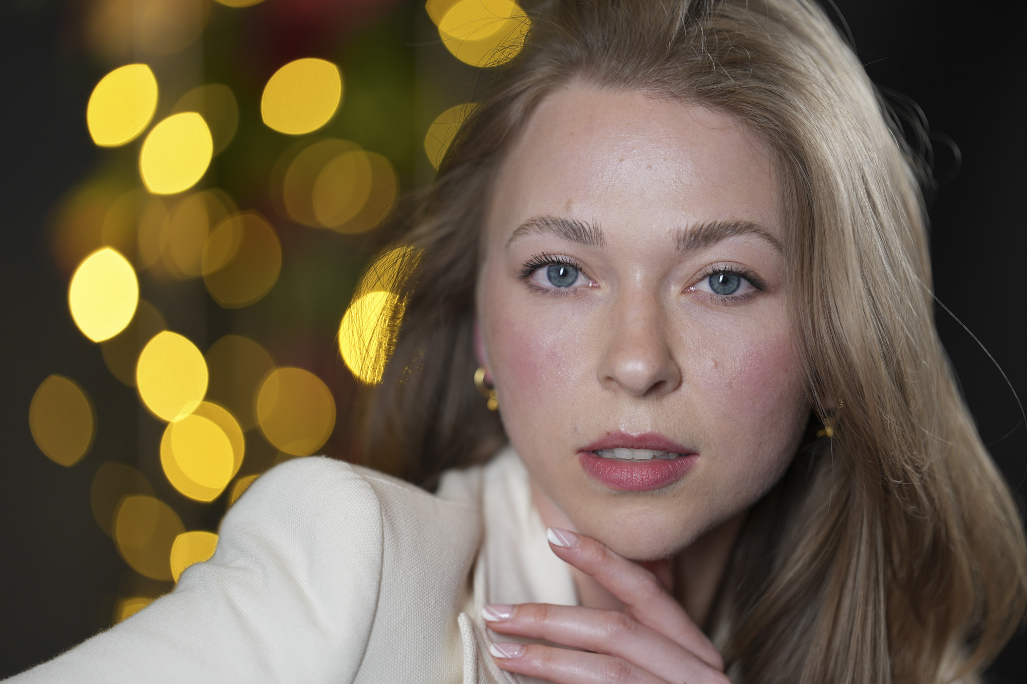 Portraits of a woman in smart jacket, in a studio with blurred fairy lights in background