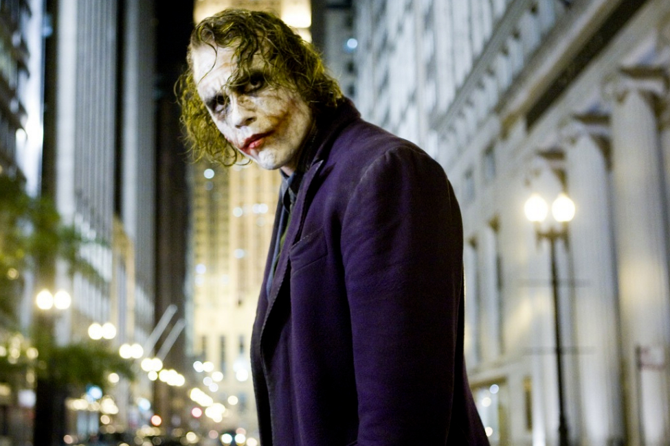 The Joker stands on the street and stares in The Dark Knight.