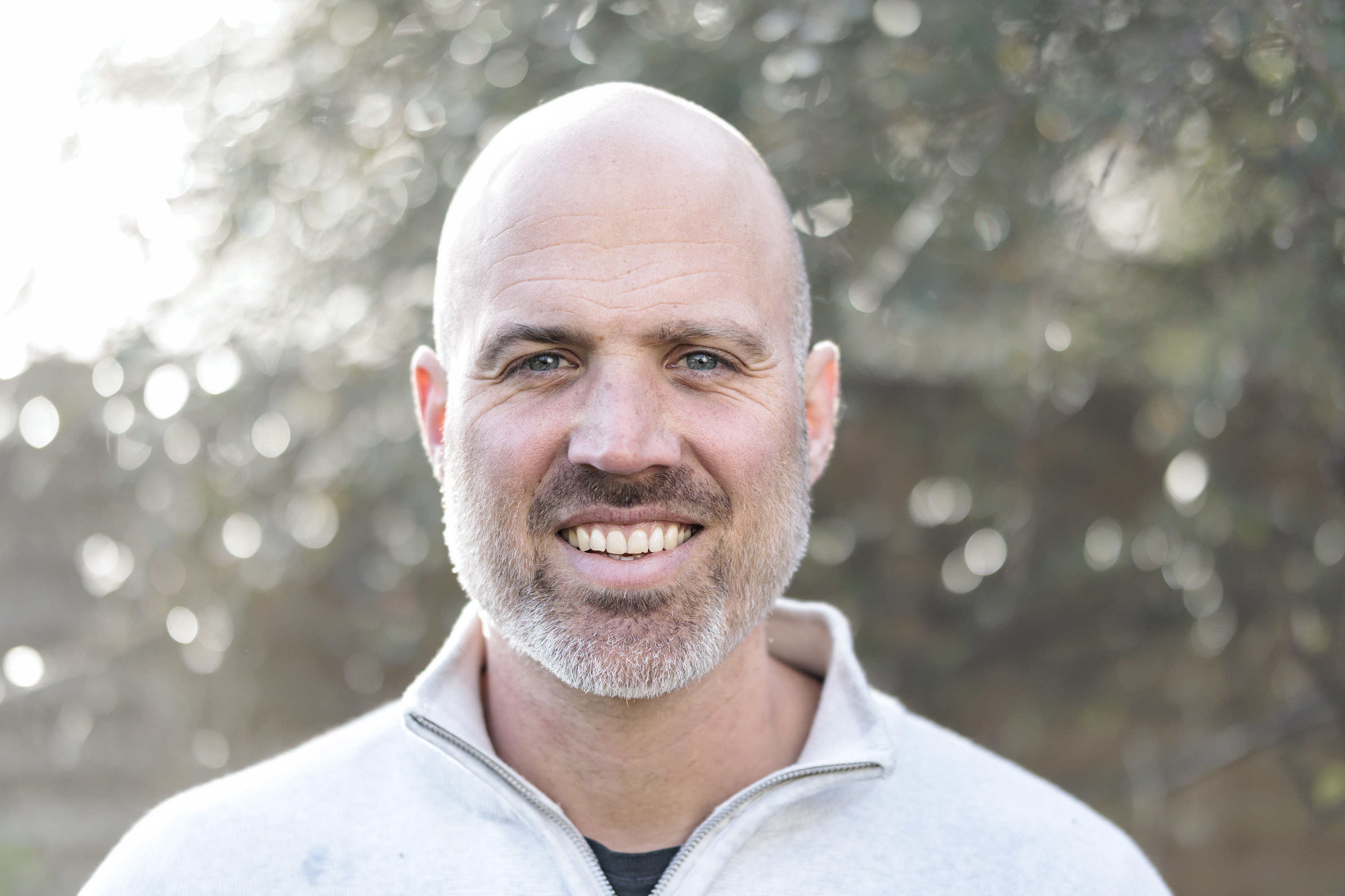 Sigma 56mm F1.4 DC DN Contemporary image gallery: head and shoulder portrait of a man during first light, with dappled light through background foliage