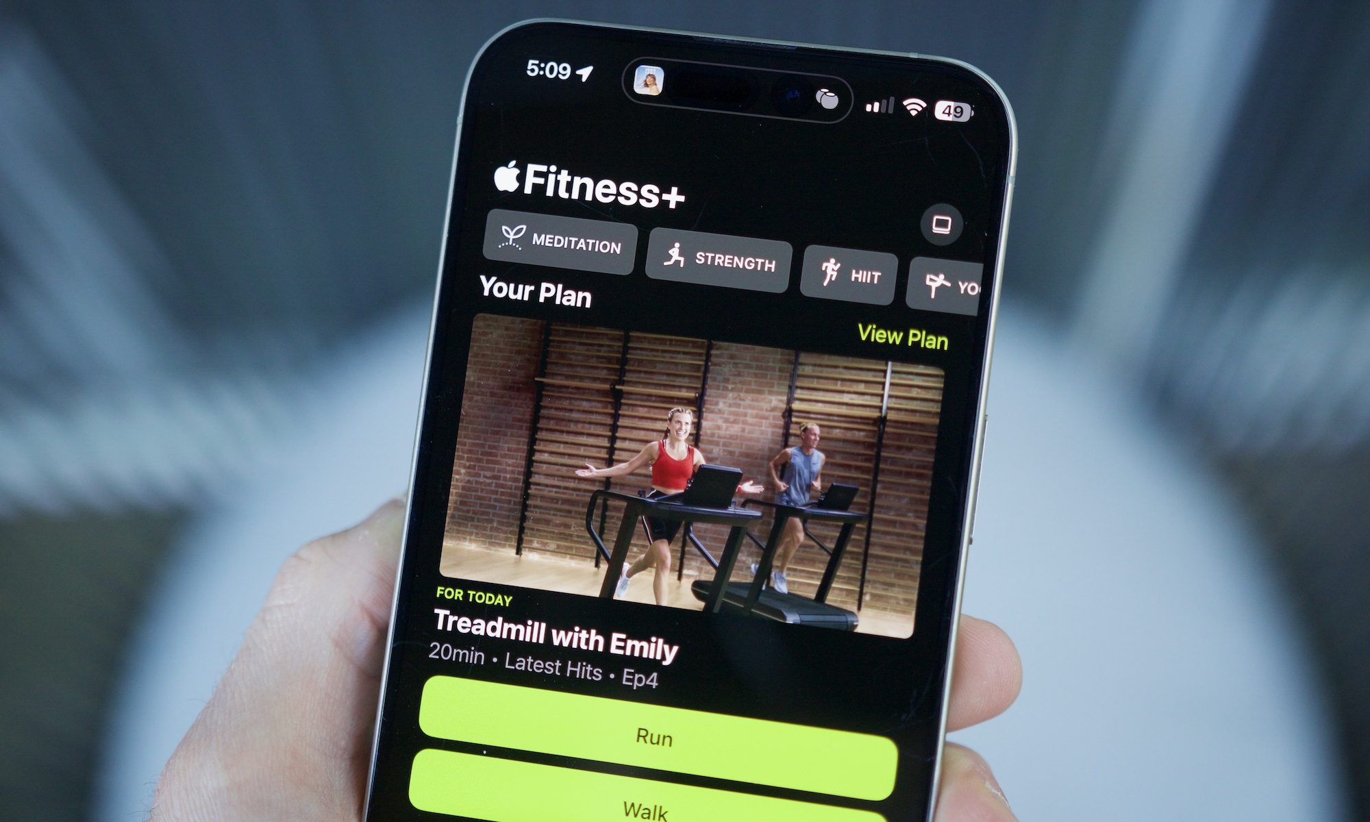 Someone holding an iPhone with the Apple Fitness app open, showing the Custom Plans feature.