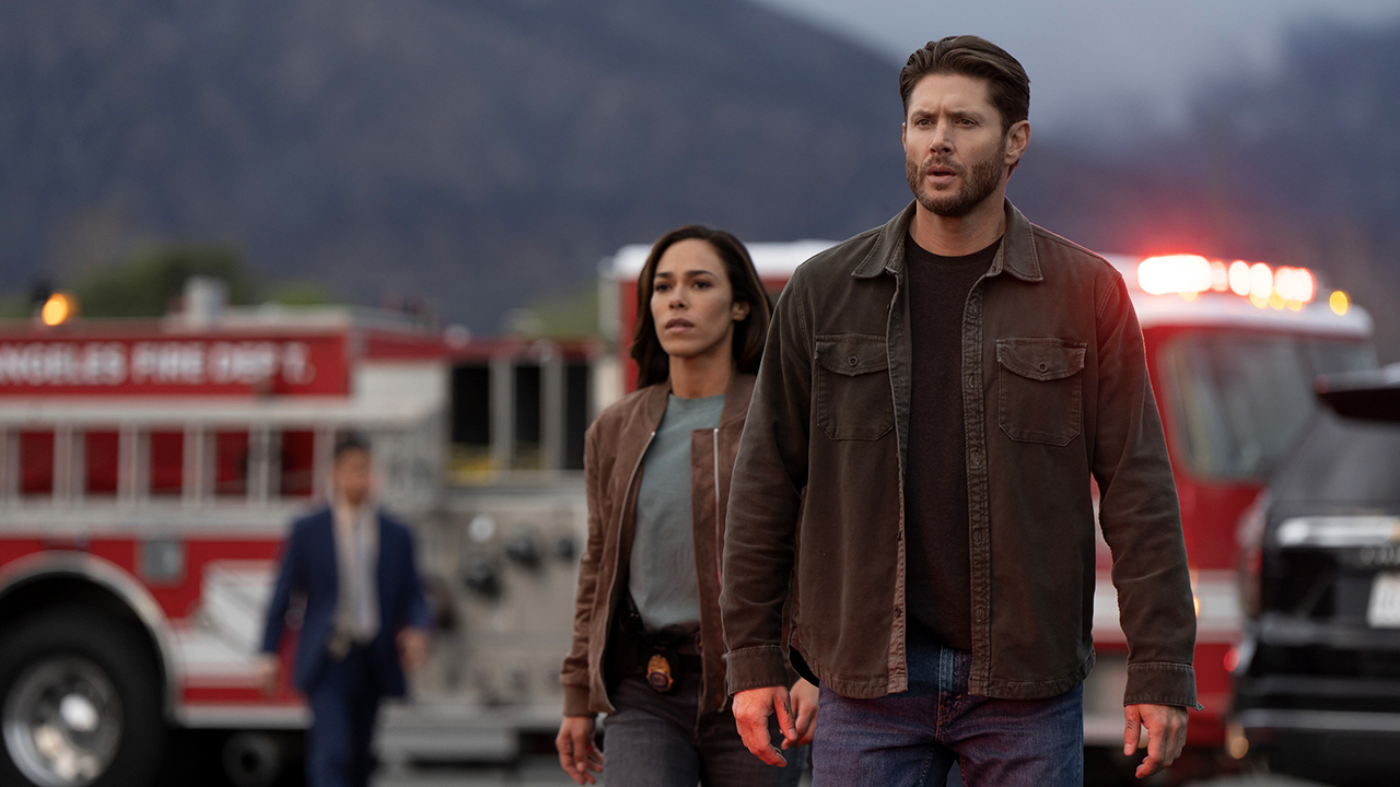 Jensen Ackles walking with a woman, firetrucks in the background in Countdown.