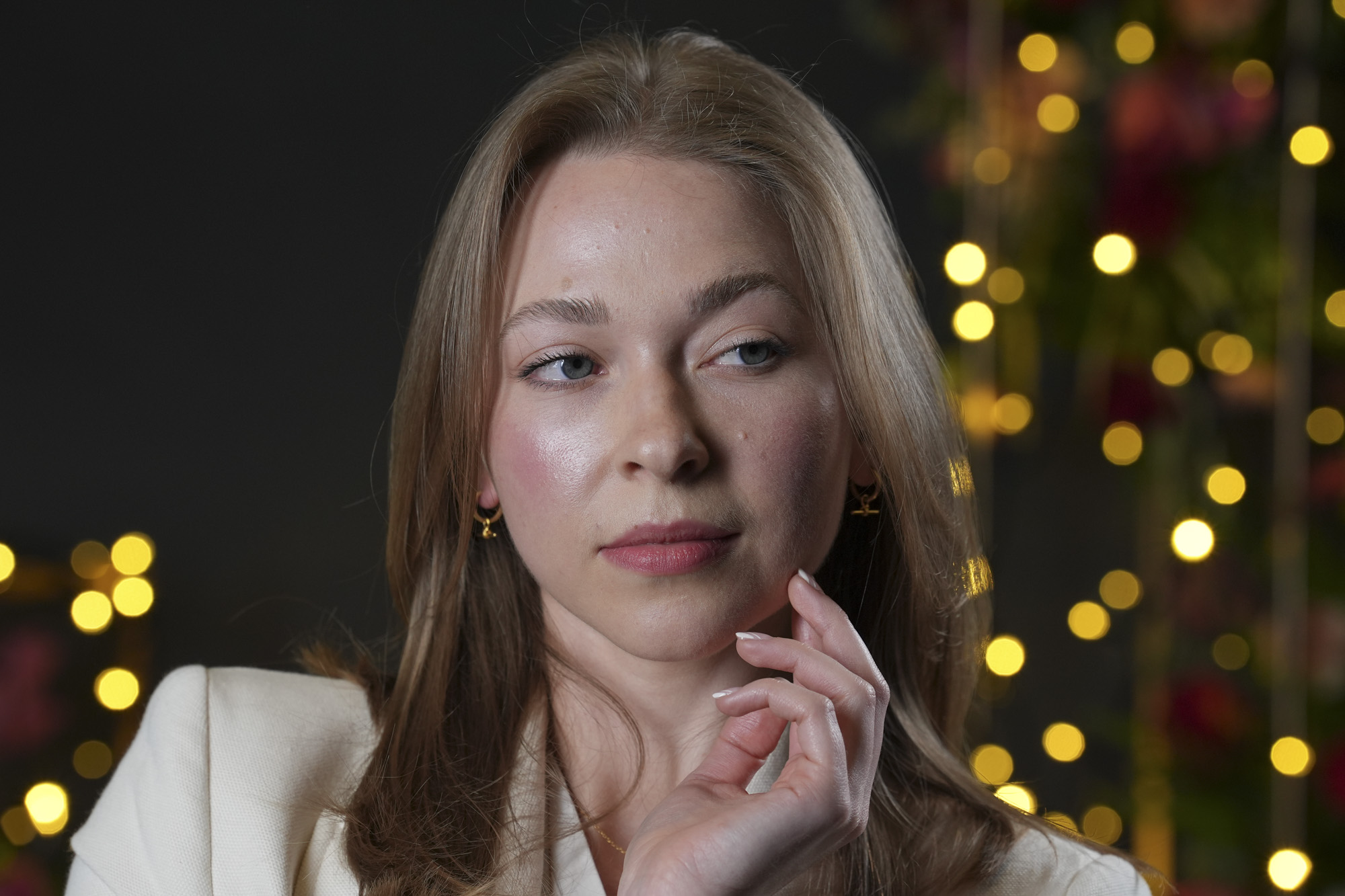 Portraits of a woman in smart jacket, in a studio with blurred fairy lights in background