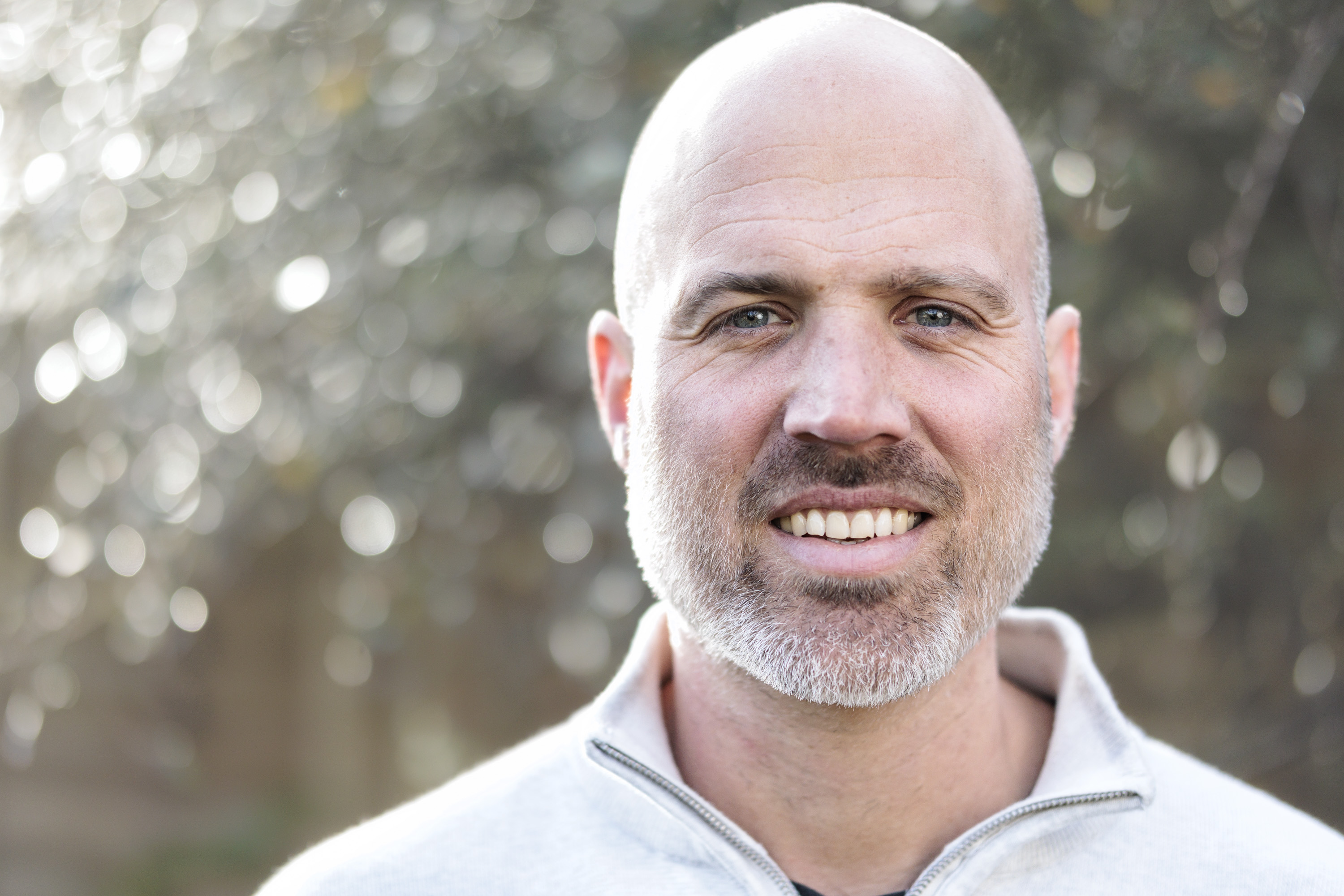 Sigma 56mm F1.4 DC DN Contemporary image gallery: head and shoulder portrait of a man during first light, with dappled light through background foliage