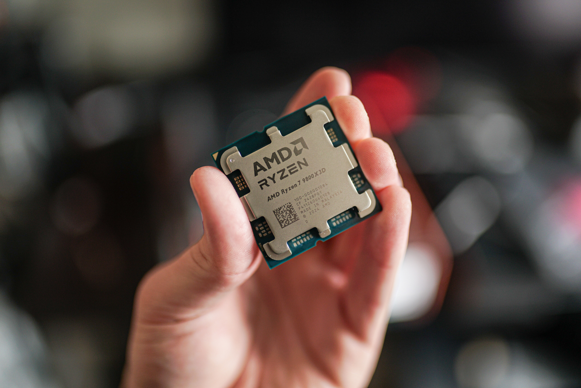The Ryzen 7 9800X3D held between fingertips.