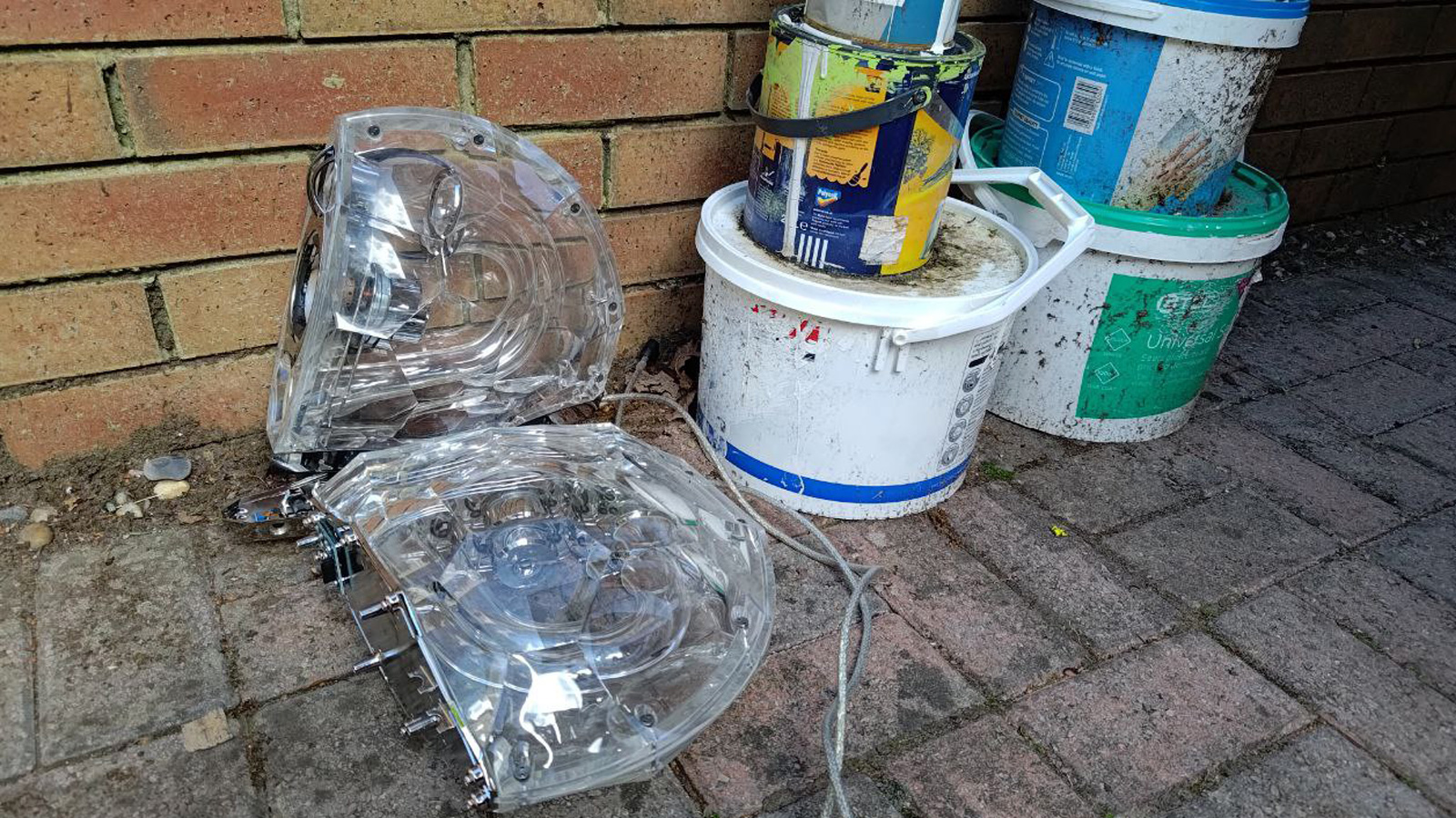 PC speakers outside by some paint tins.