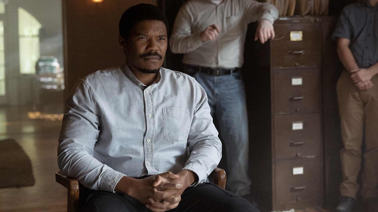 Perlie in a white shirt sitting down in an office in The Walking Dead: Dead City.