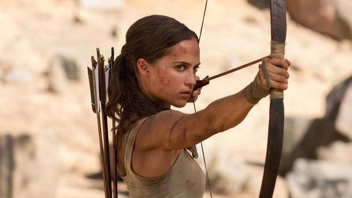 Alicia Vikander as Lara Croft holds a bow and arrow in Tomb Raider.