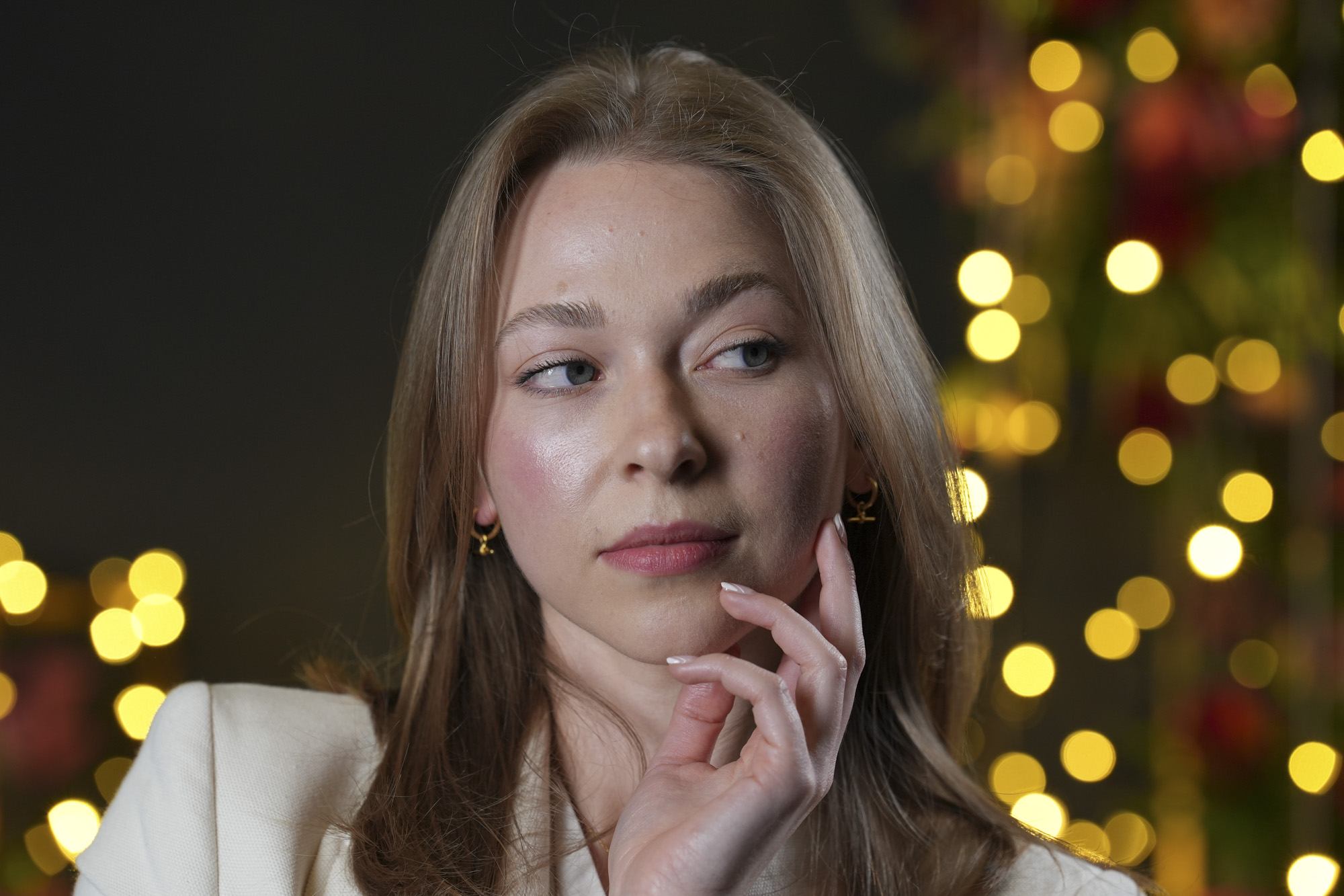 Portraits of a woman in smart jacket, in a studio with blurred fairy lights in background