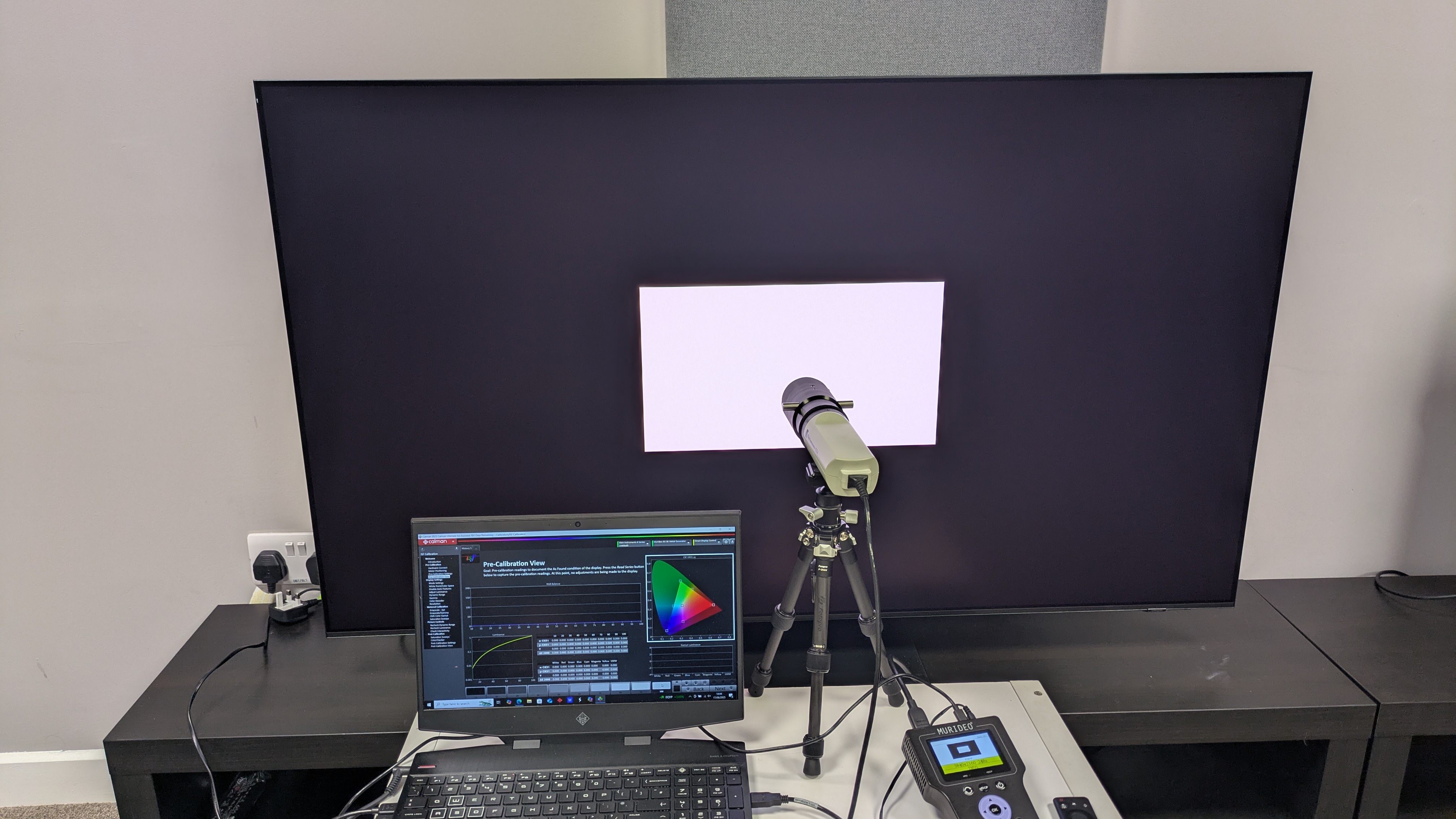 Samsung S95F with testing equipment connected and displaying white window test pattern 