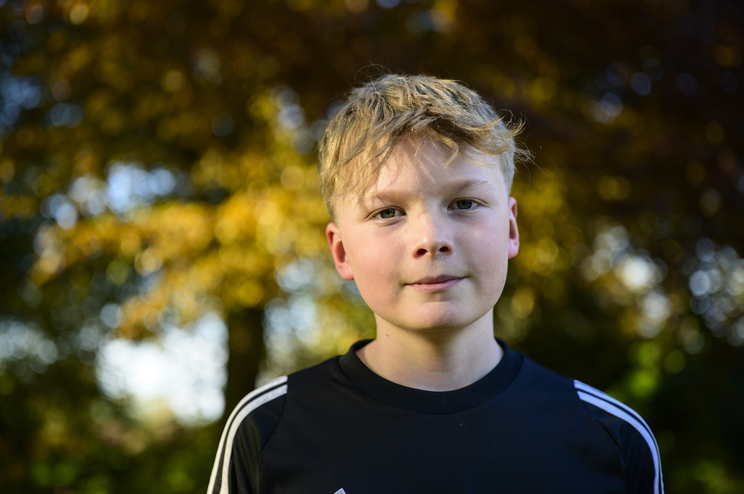 Portrait of a young man during golden hour with dappled light through trees, taken with the Viltrox AF 50mm F2 Air lens