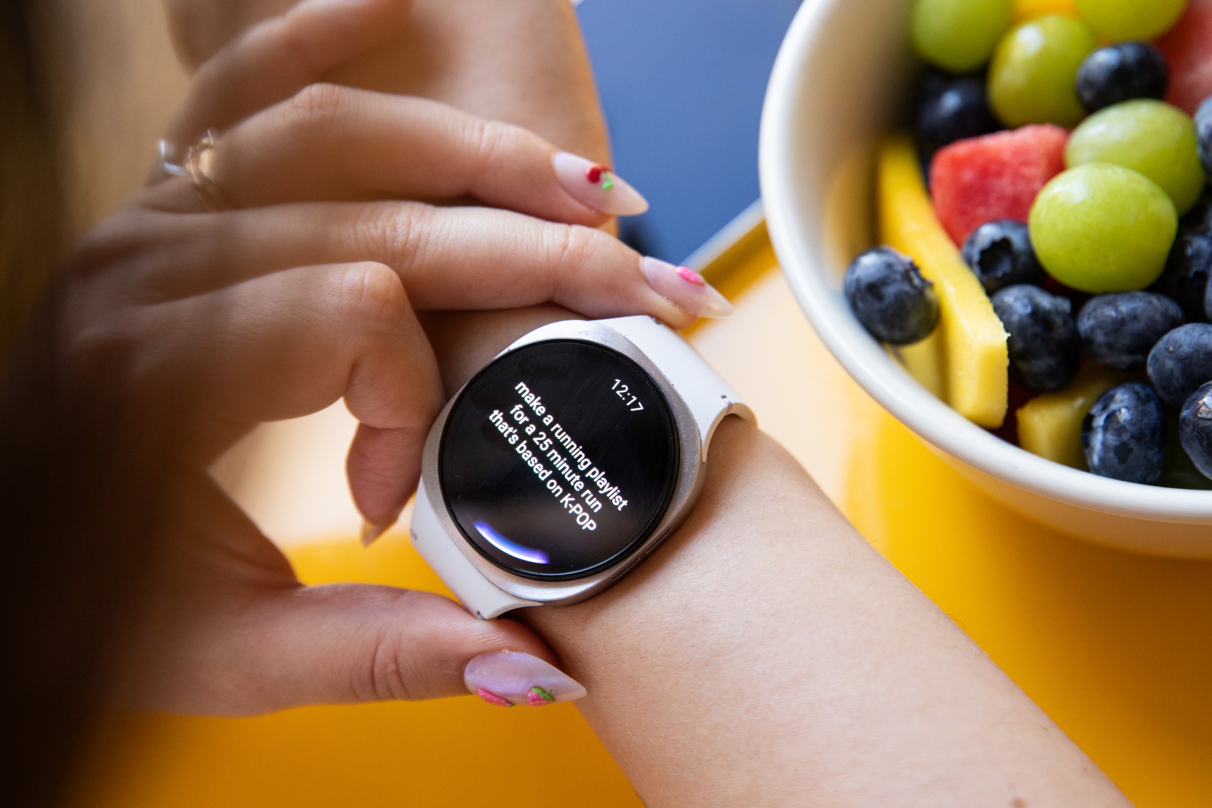 View of a person asking Gemini to make a running playlist based on K-pop. There’s a bowl of fruit in the background in the upper-left corner