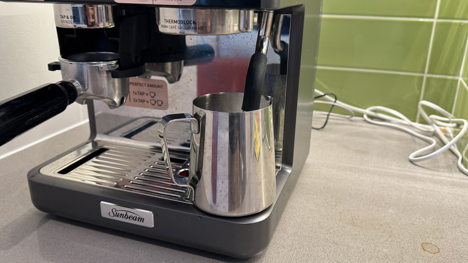 A milk pitcher with the steam wand of the  Sunbeam Origins Sense inserted