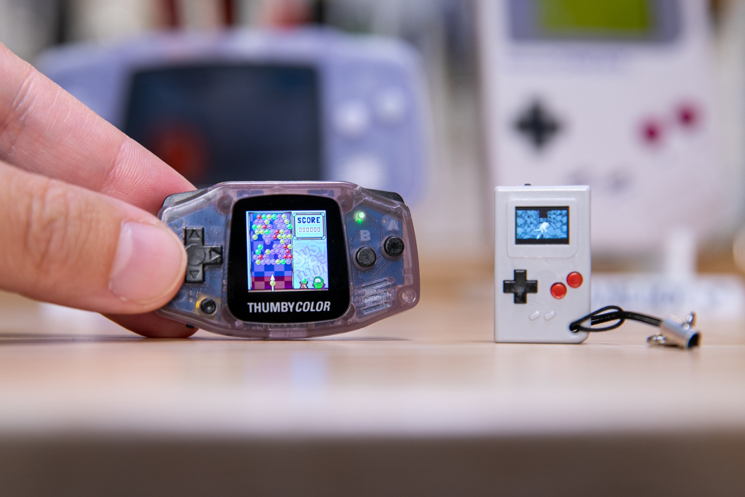 The Thumby Color, playing a Bust-A-Move clone, with thumb for scale.