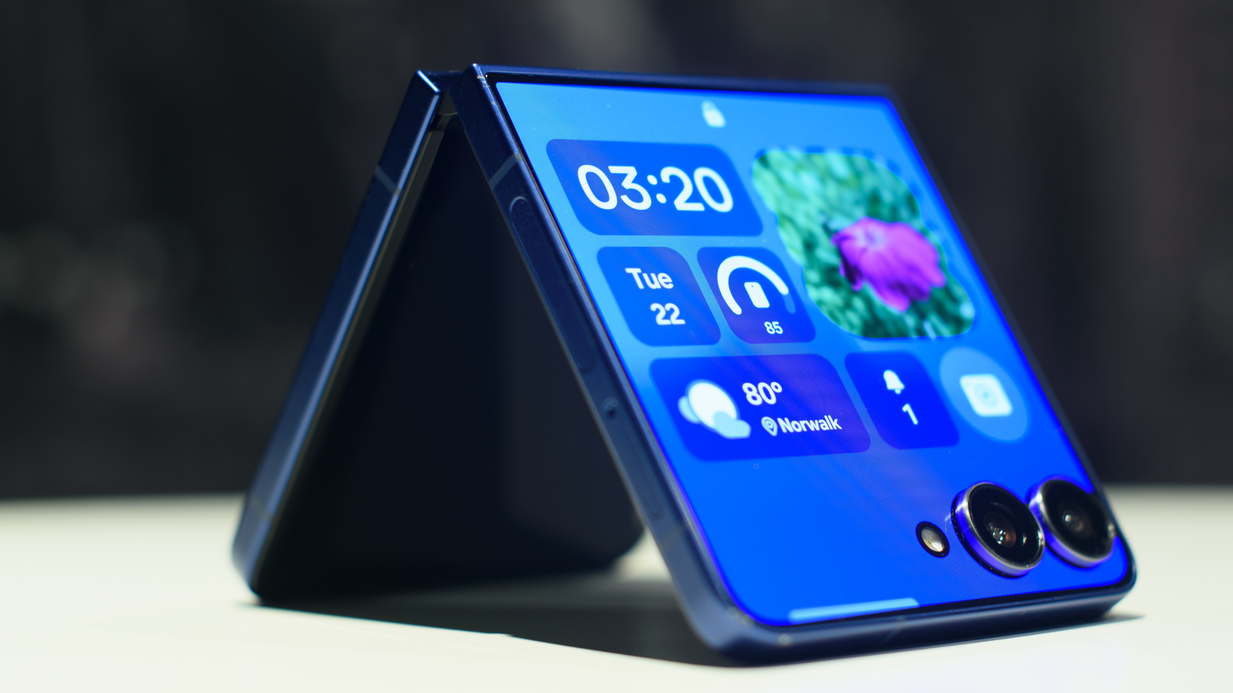Samsung Galaxy Z Flip 7 in blue folded showing widgets on the cover display