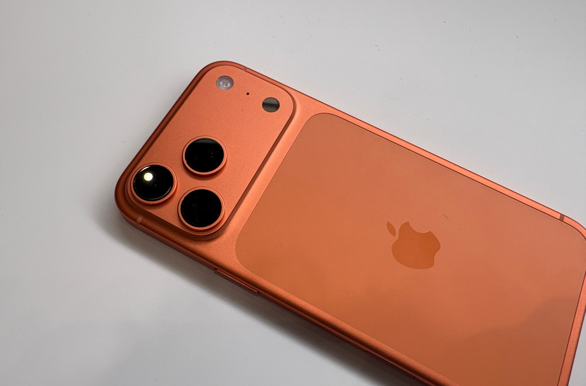 The iPhone 17 Pro in Cosmic Orange lying on a table.