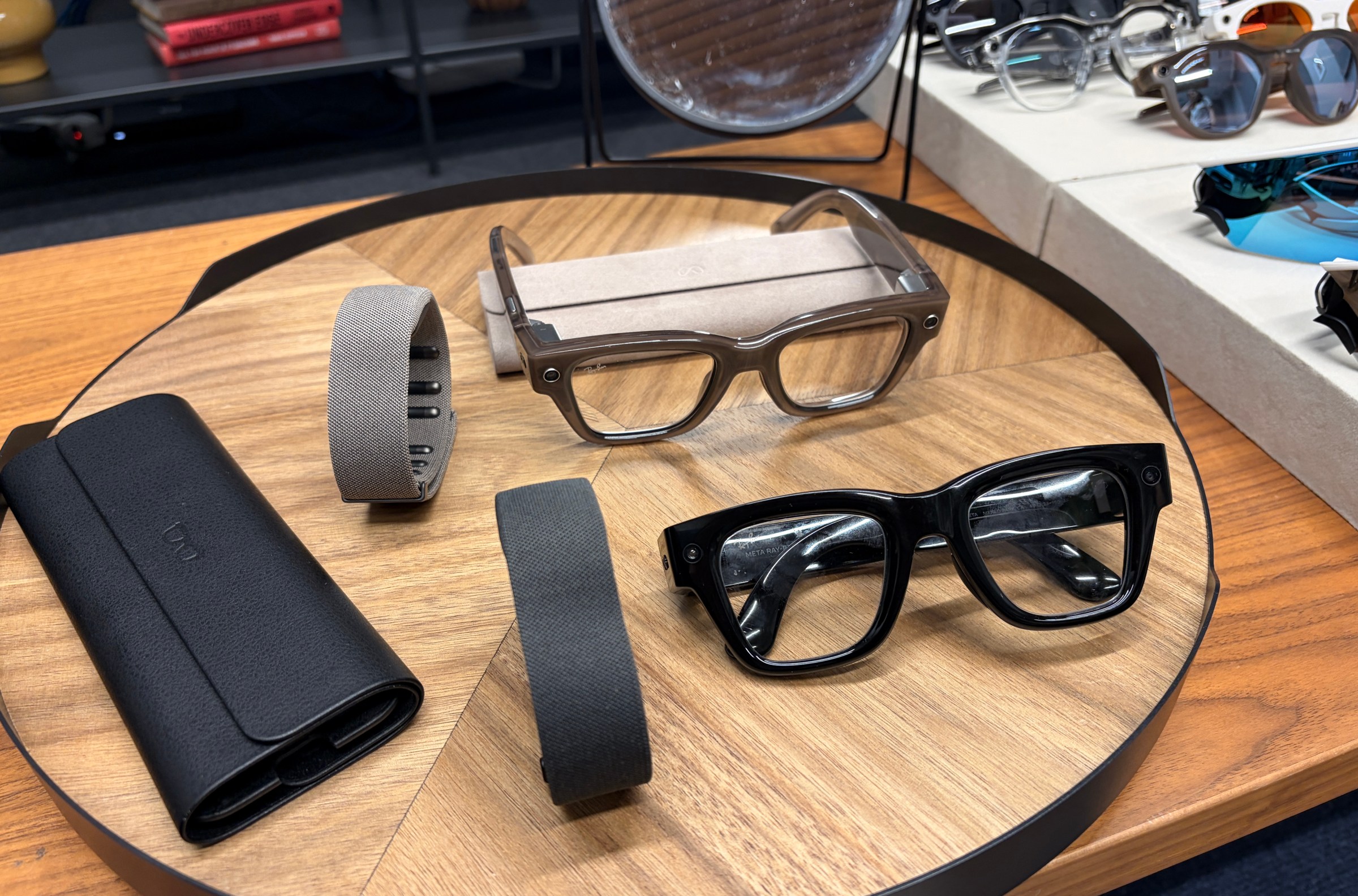 The Meta Ray-Ban Display in black and sand, with the accompanying neural wristbands and collapsible cases.