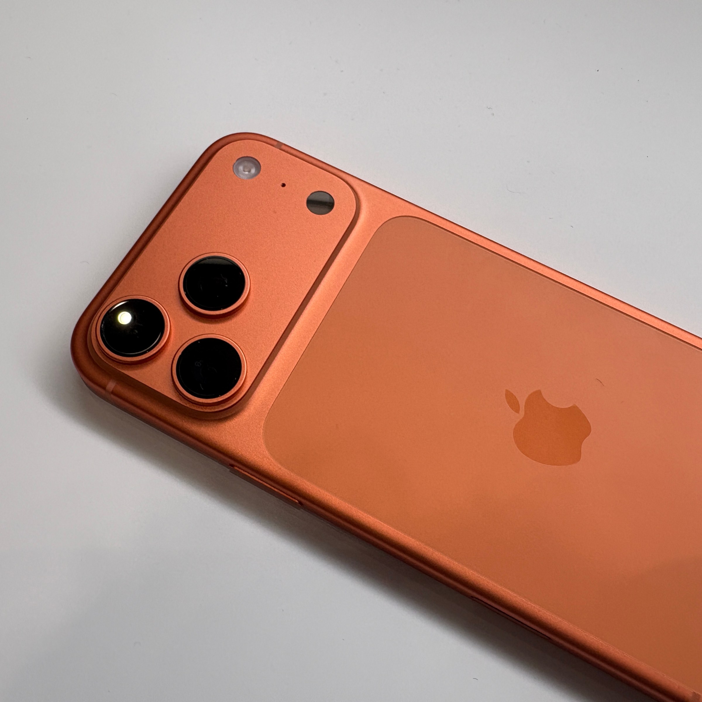 The iPhone 17 Pro in Cosmic Orange lying on a table.