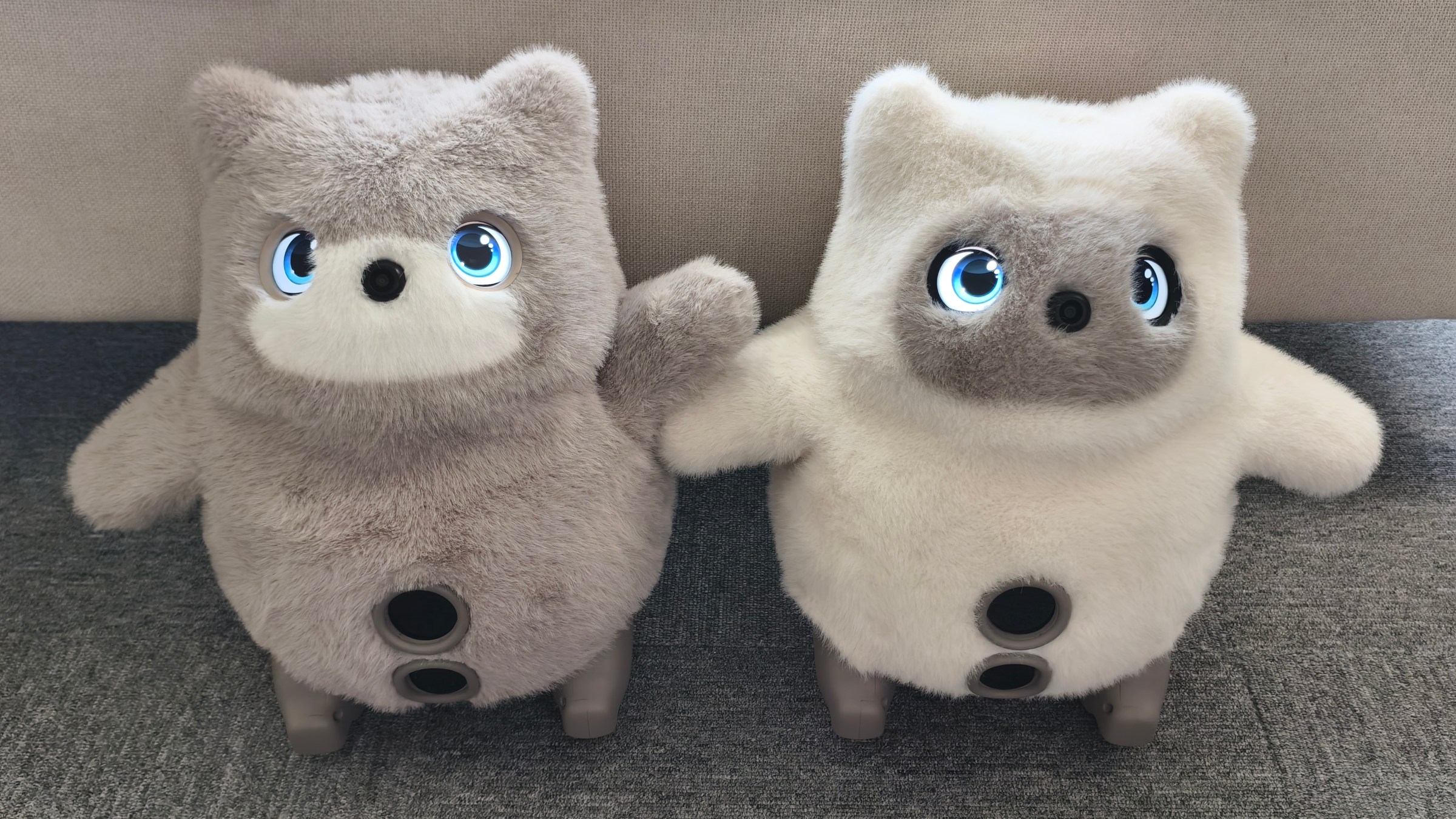 A pair of robots with large LCD eyes covered in fur.