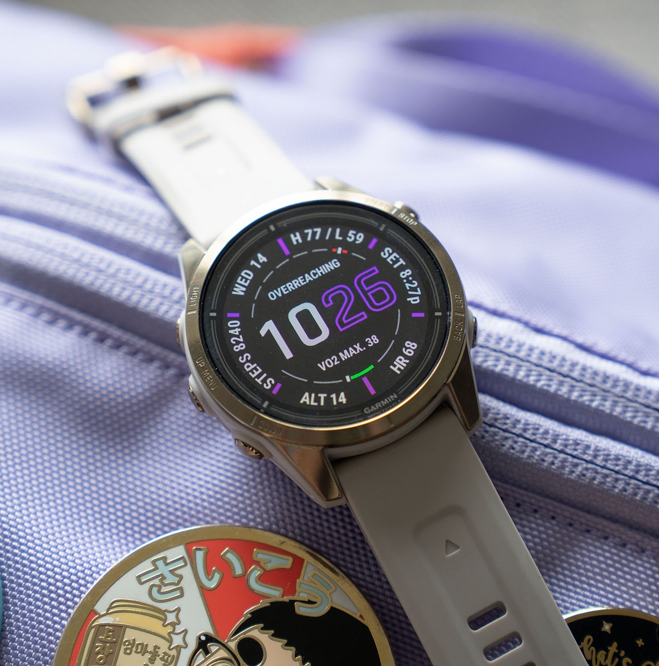 The 42mm Garmin Epix 2 Pro on top of a lavender bag with enamel pins.