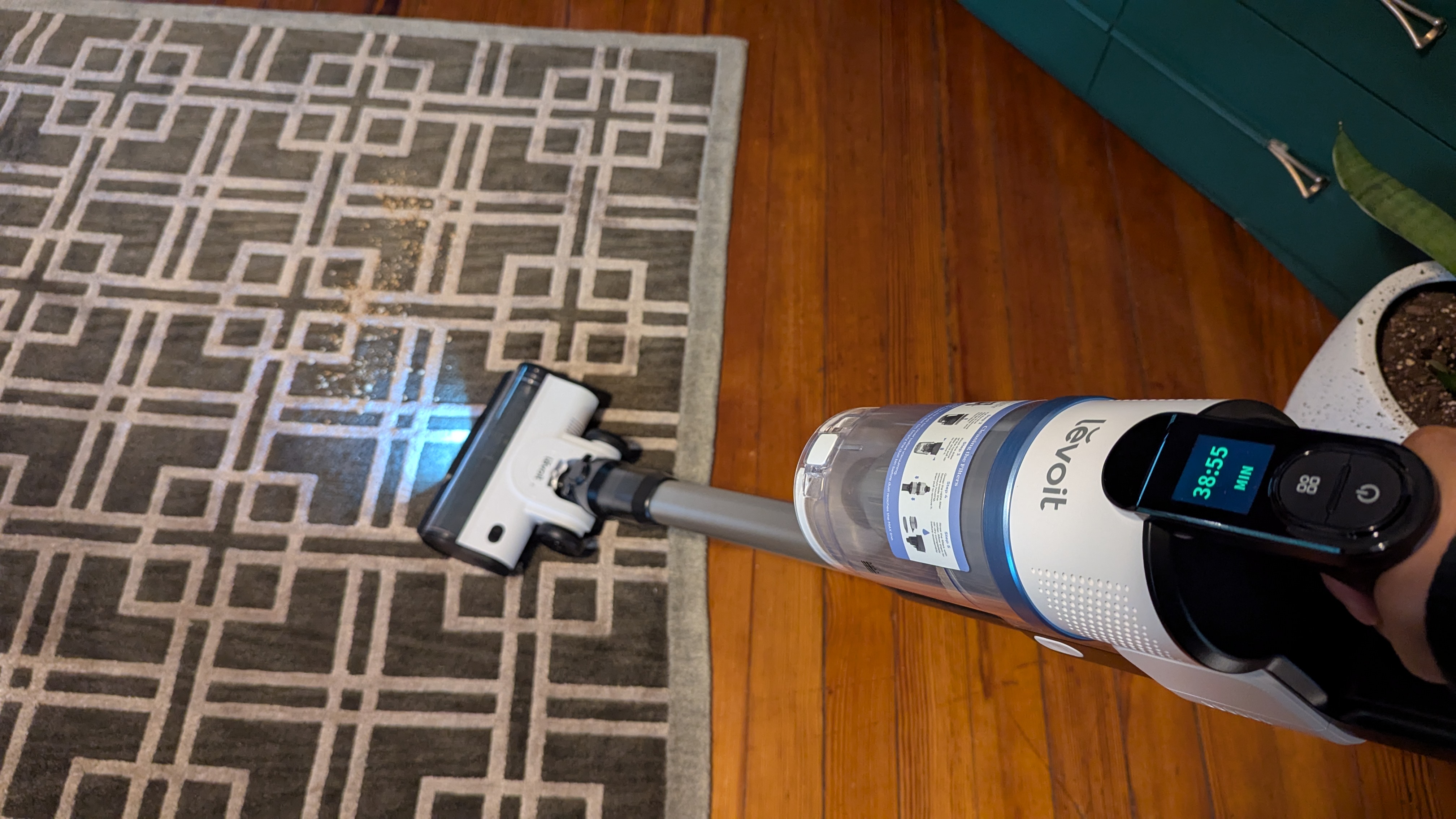 Levoit Aero vacuum being used to clean debris from a patterned rug