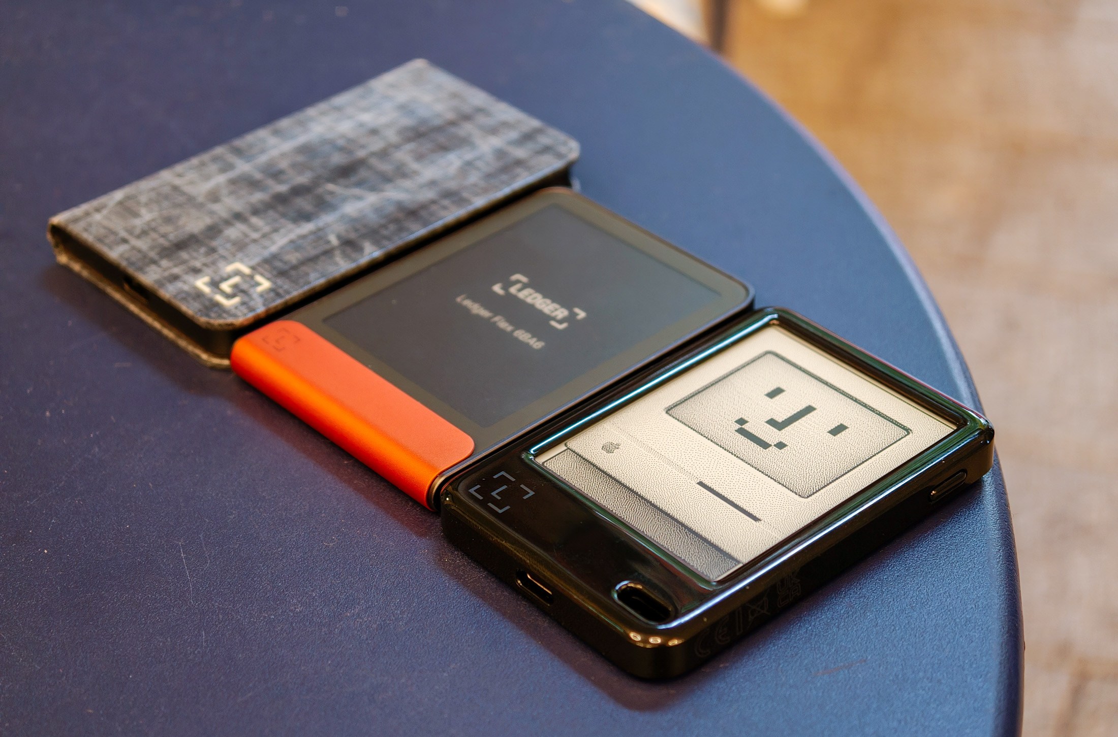 Ledger Nano Gen5, Ledge Flex, and Ledger Stax resting on a blue table together