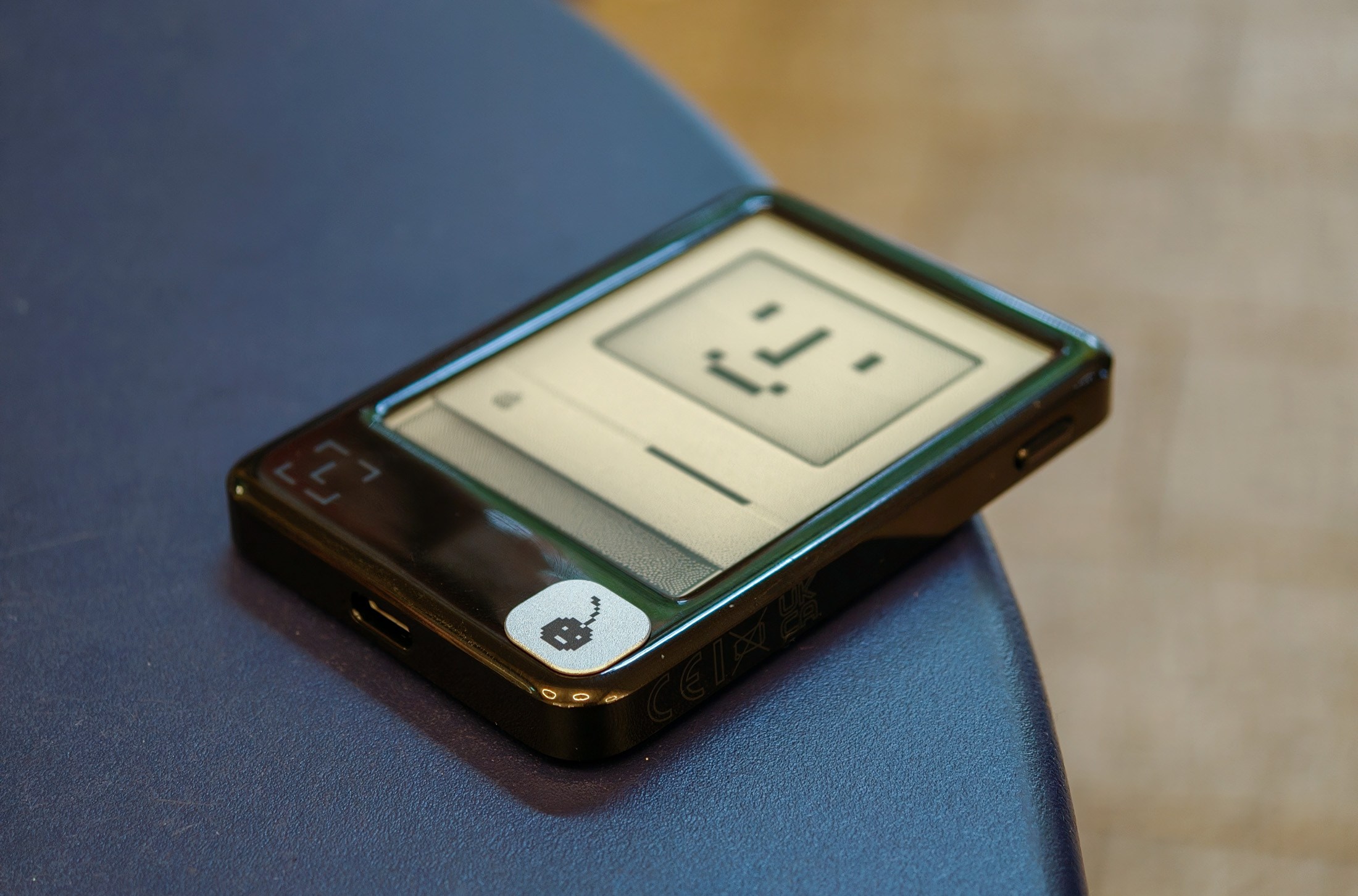 Ledger Nano Gen5 featuring a badge with a cherry icon designed by Susan Kare, lying on a table