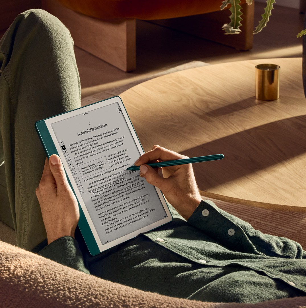 A person on a couch reading on a Kindle Scribe.