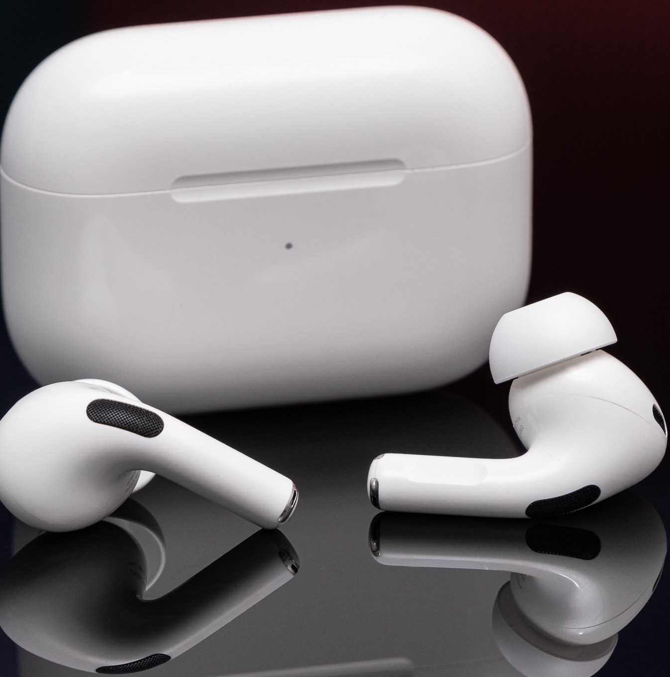 Apple’s second-generation AirPods Pro photographed on a reflective black surface.