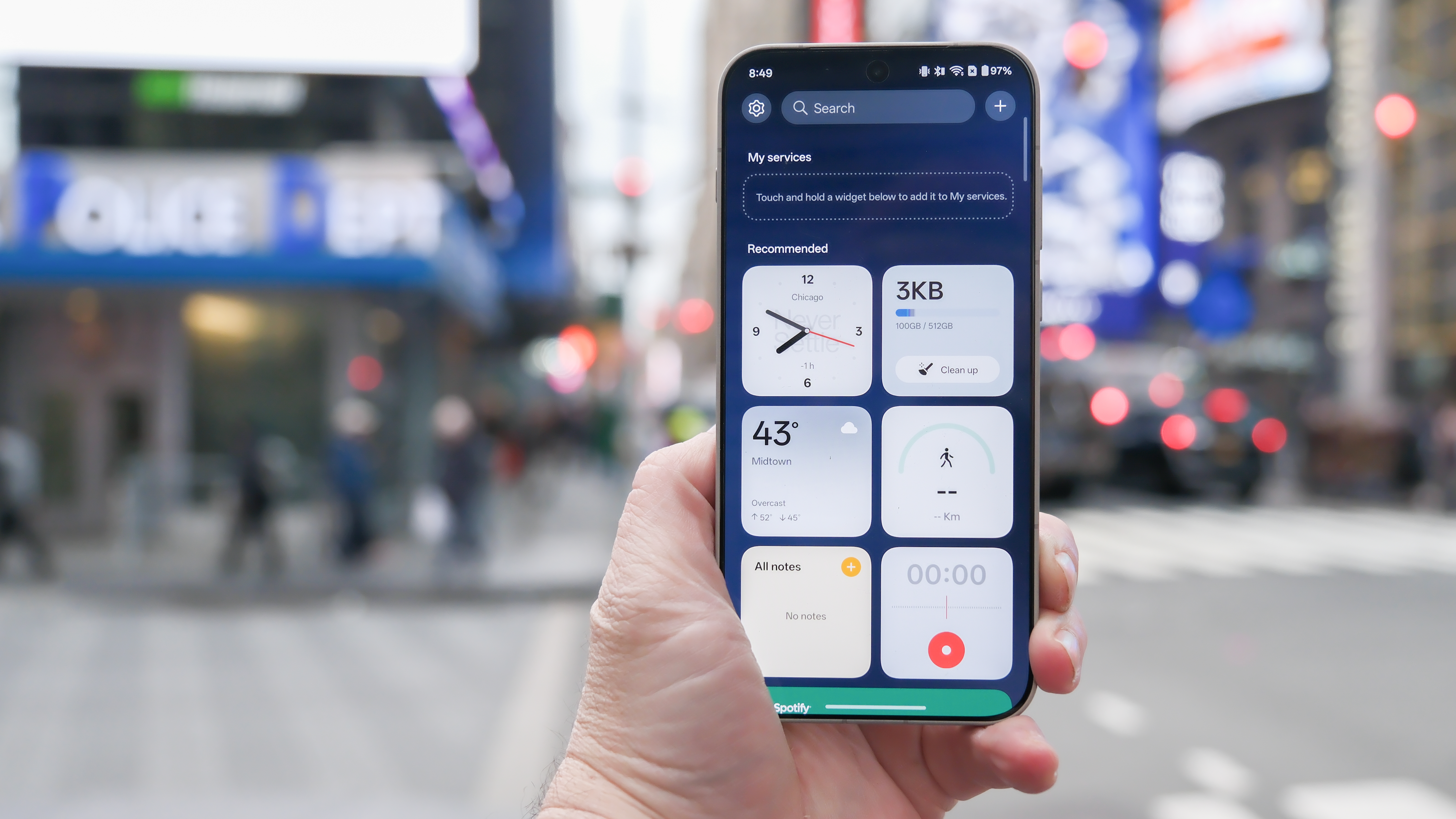 OnePlus 15 in Times Square New York City on the busy street showing the cameras and sides of the phone in addition to home screen panels and Settings menus